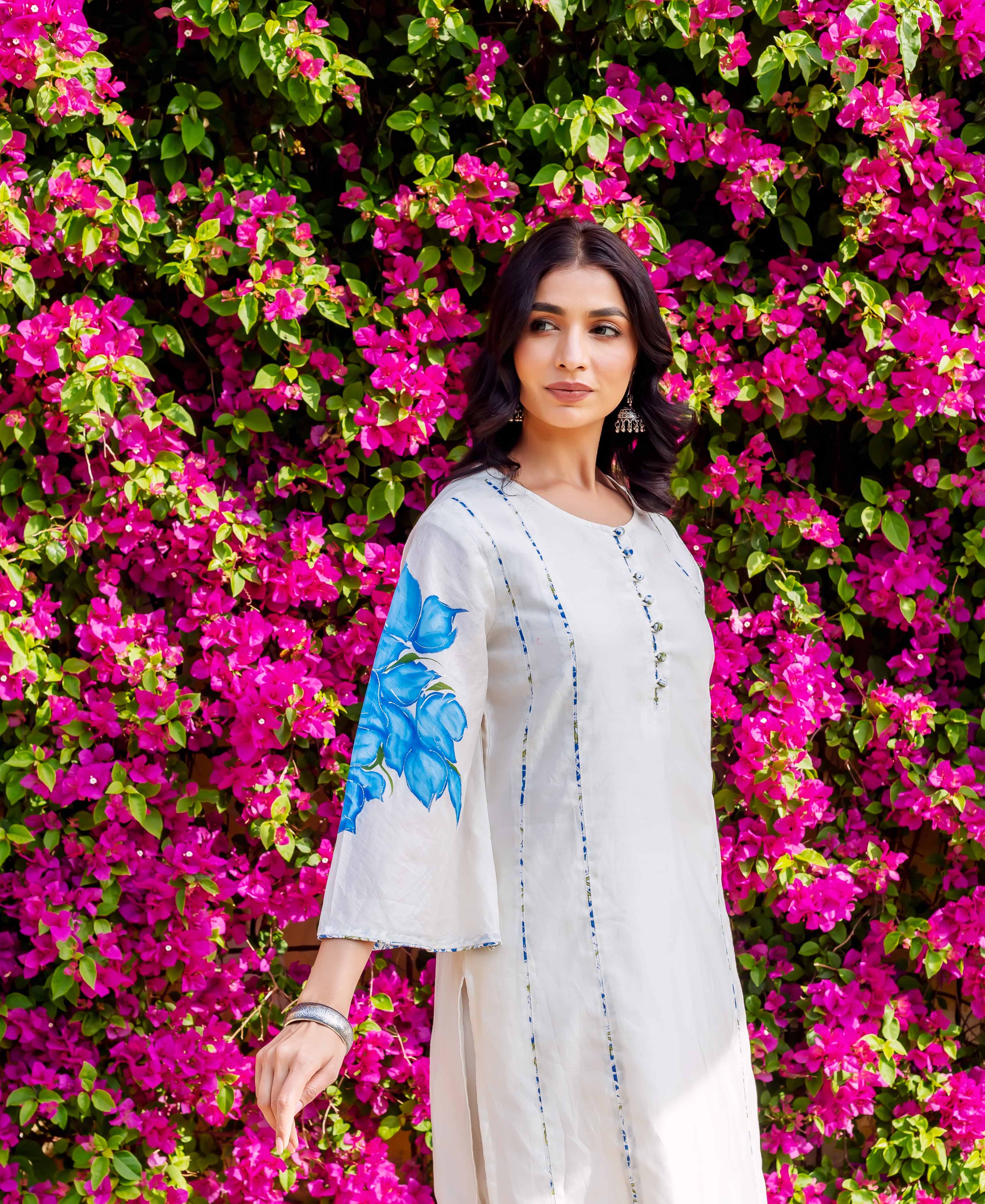 White kurta with blue brush-painted floral sleeves and subtle vertical stripes on model.