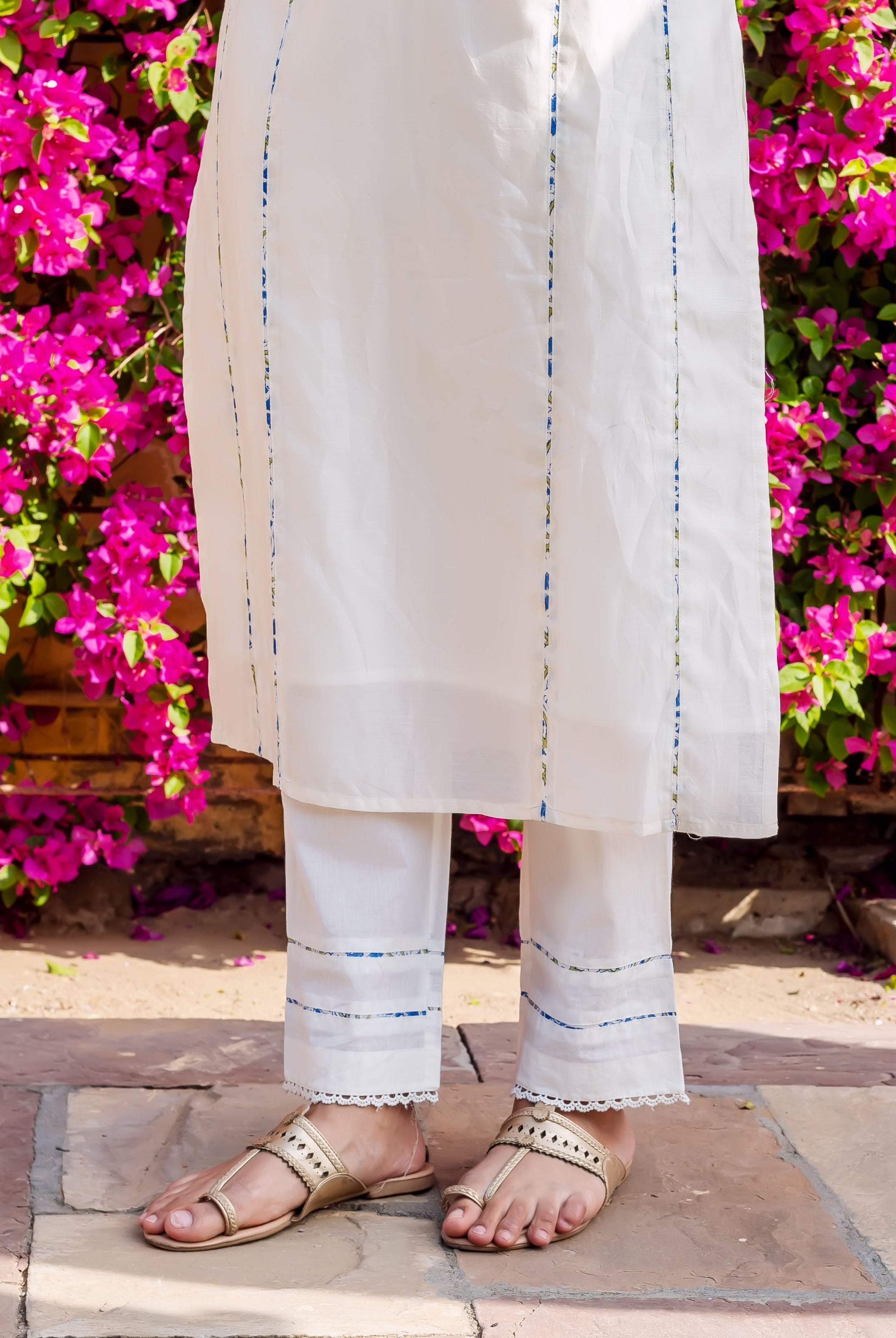 White kurta with blue and gold brush painted stripes, paired with matching white pants.