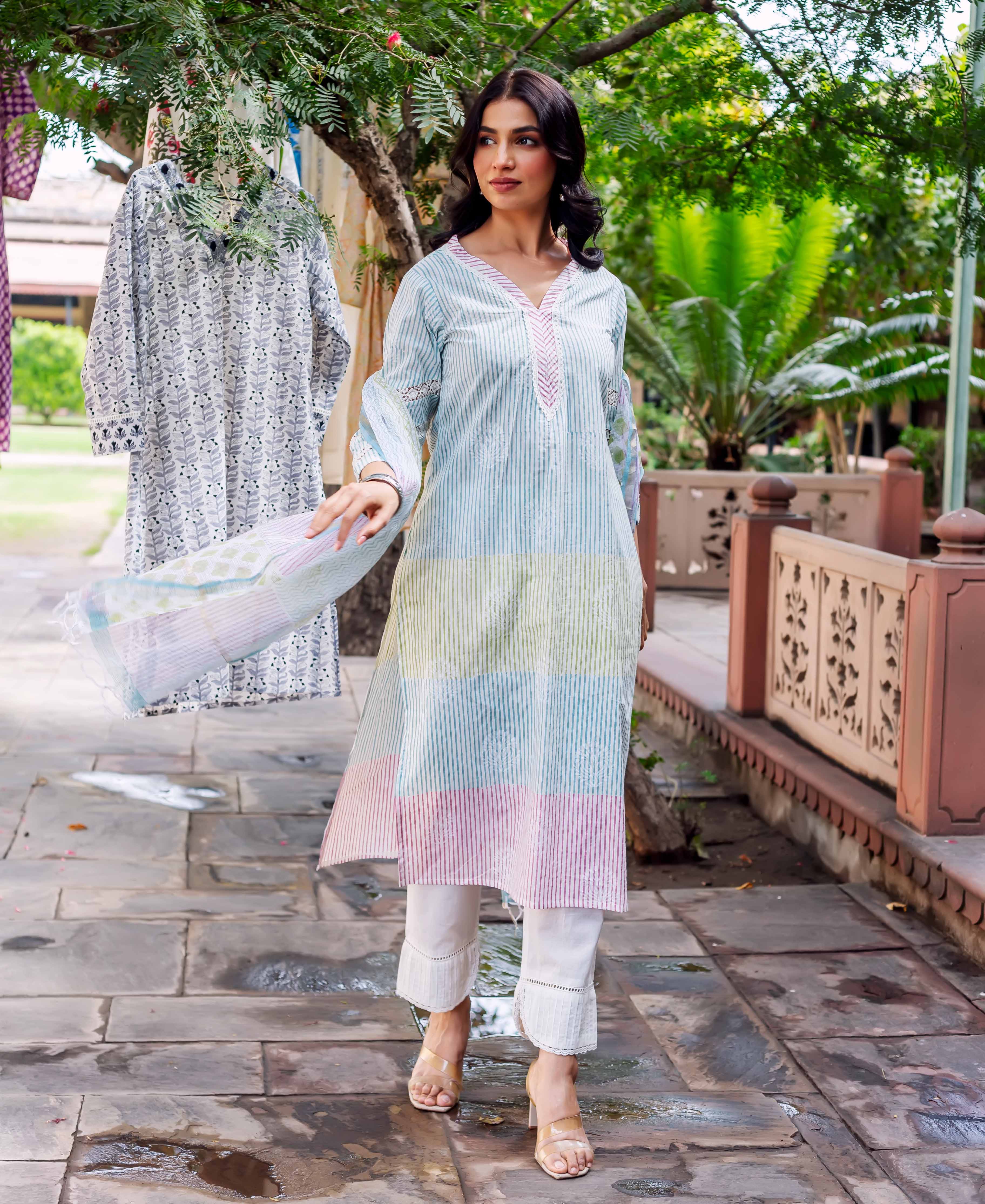 Woman wears pastel Aisha Cotton Kurta with hand block print, white pants and heels outdoors.
