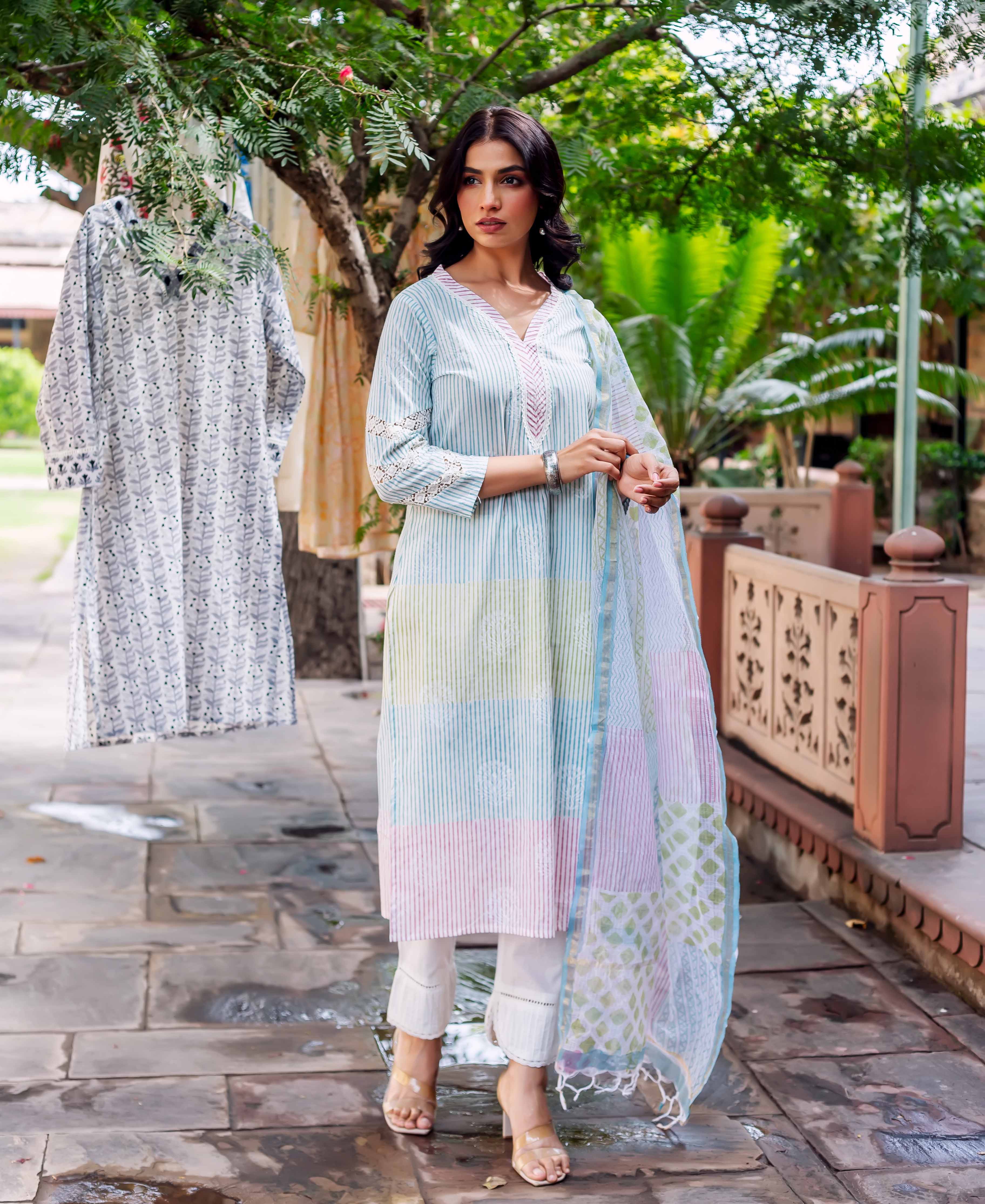 Woman in pastel striped kurta with white pants and dupatta outdoor setting.