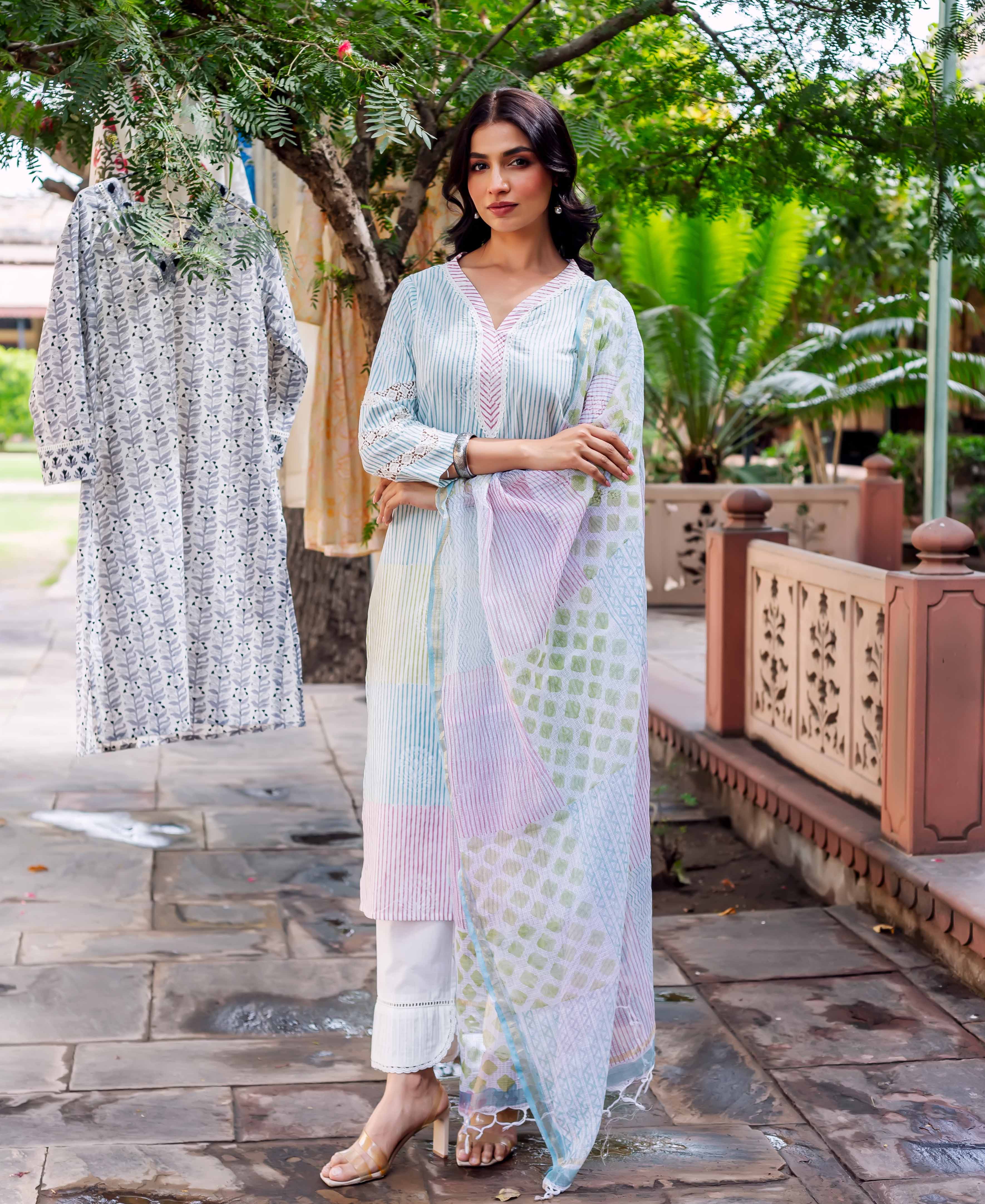 Woman in pastel kurta with block-printed pastel dupatta and white pants standing outdoors.