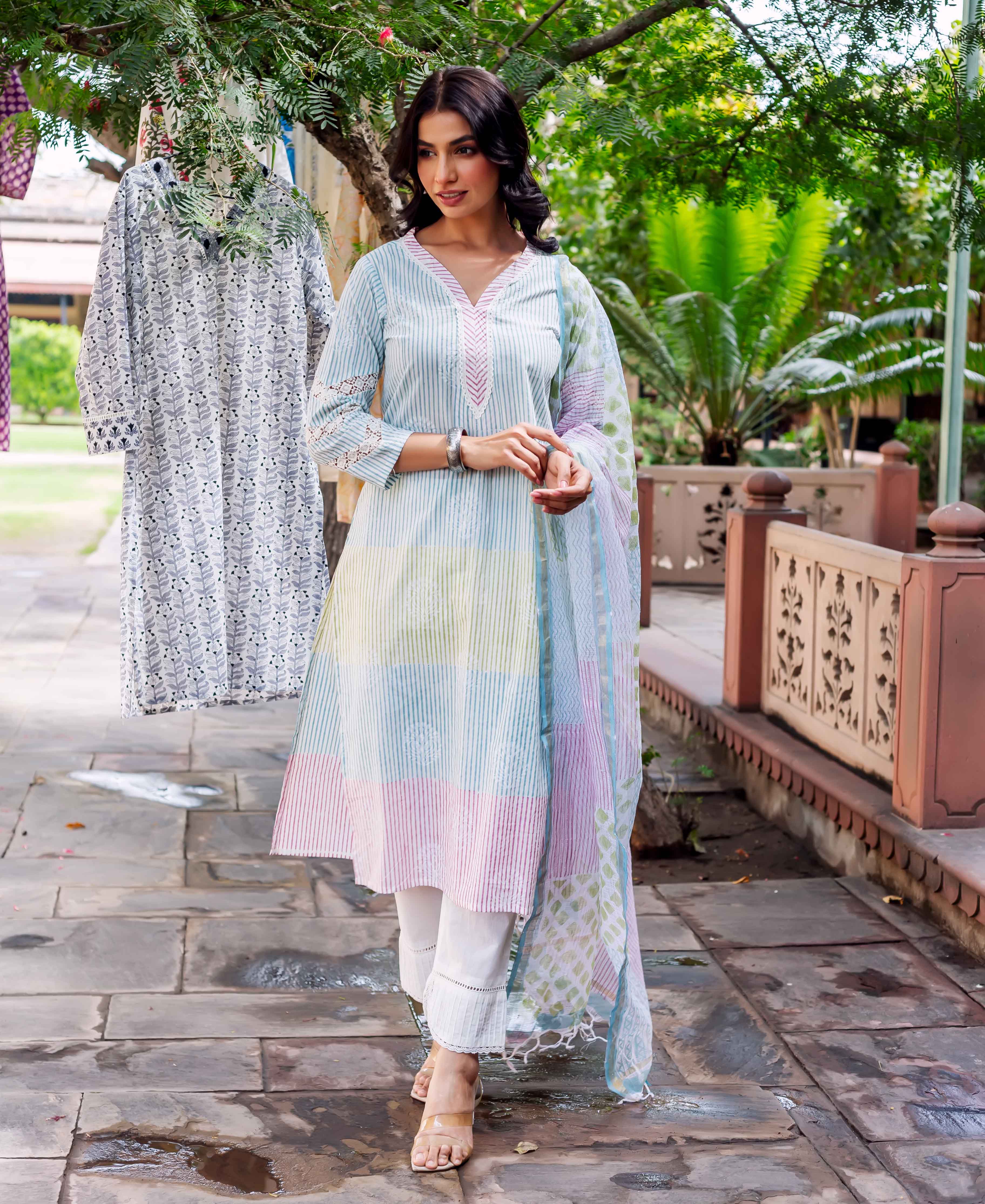 Full-length photo of a woman in a pastel striped hand-block printed kurta set with white pants.