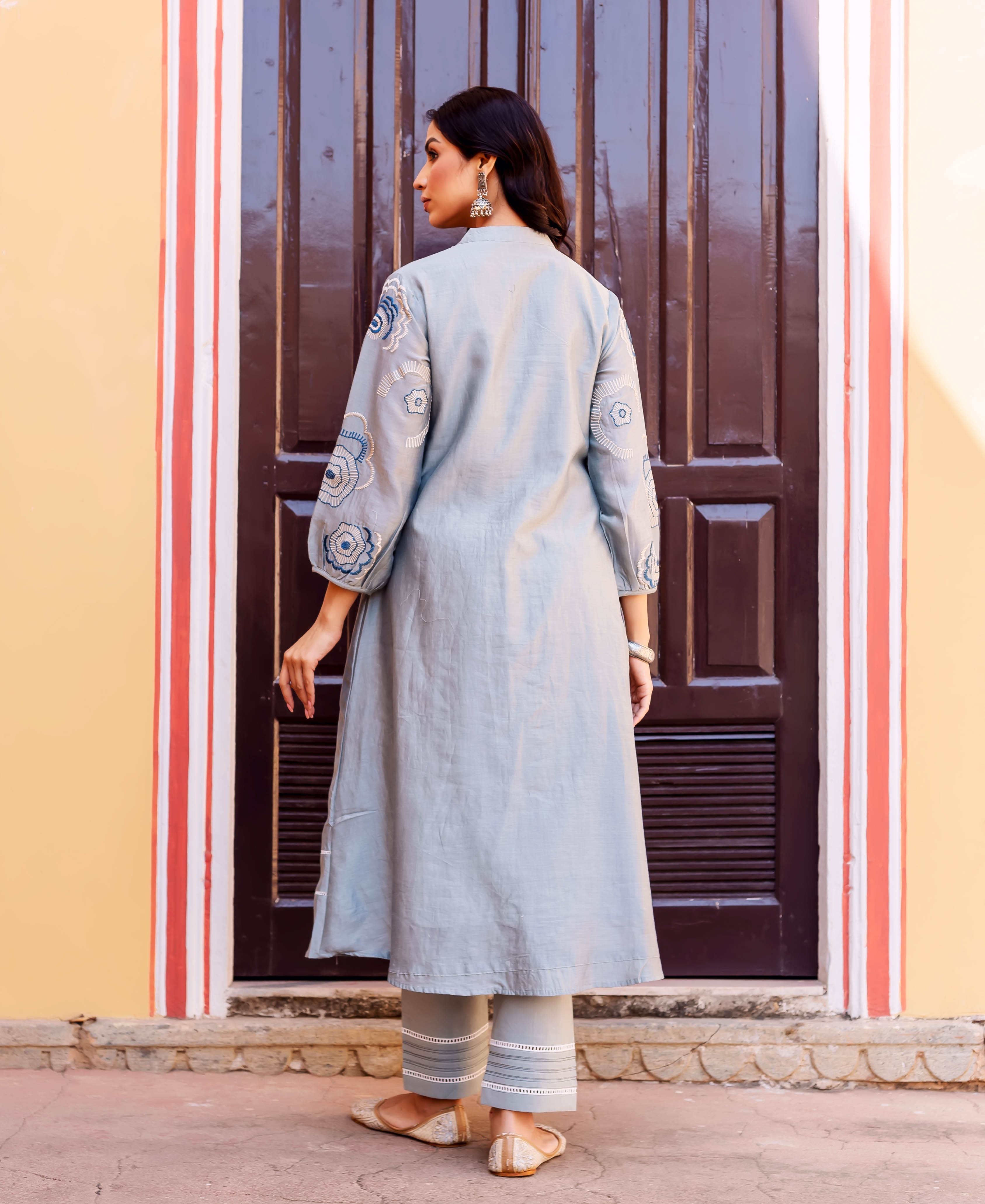 Back view, model wearing a slate blue kurta with circular hand-block-printed ethnic patterns.