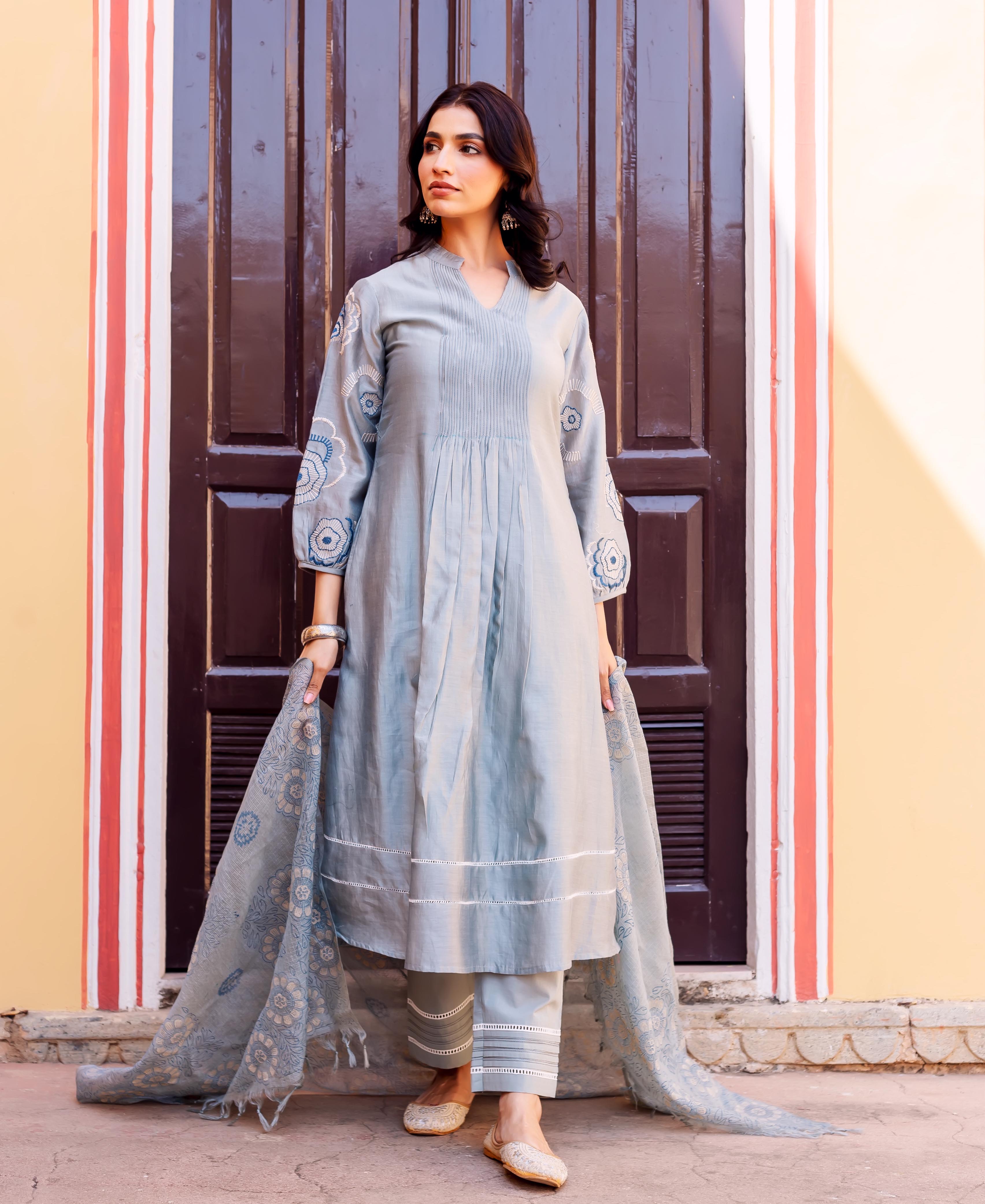 Woman wearing a slate blue pleated kurta set with blue patterned sleeves and dupatta.