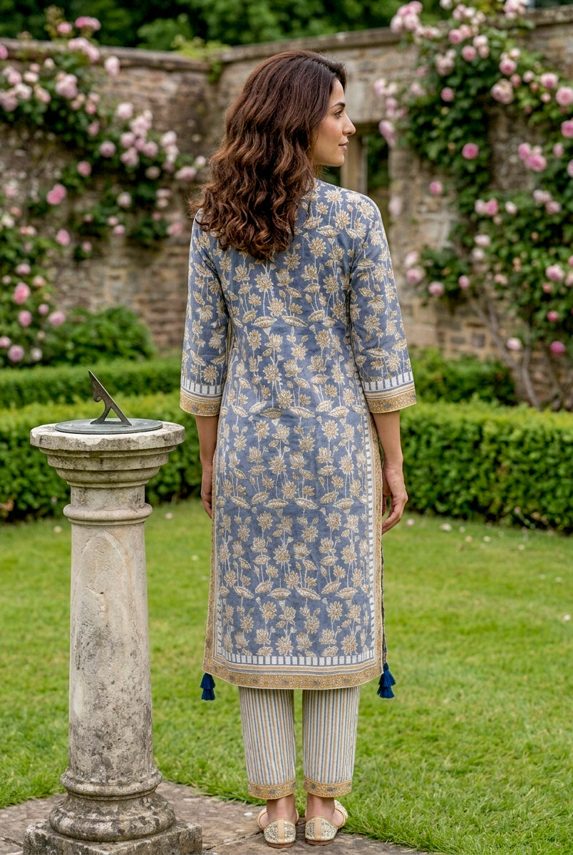 Back view of model wearing dusty blue hand-block print kurta with floral motifs and striped pants.