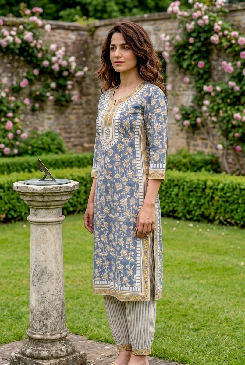 Model in dusty blue floral hand block print kurta set with striped Afghani salwar, side.