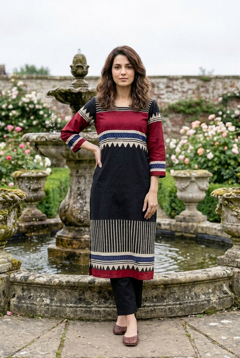 Front view of woman in black and maroon tribal hand block print kurta set.