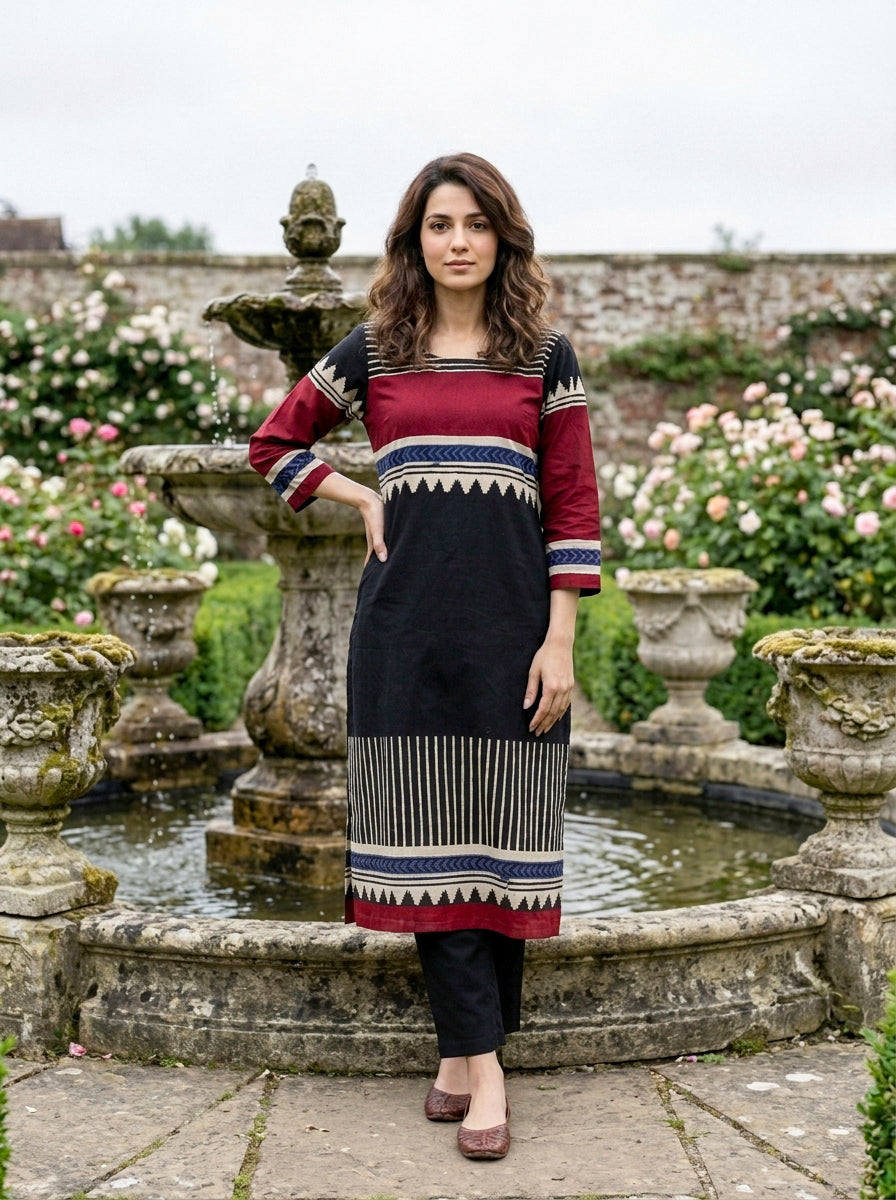 Front view of woman in black and maroon tribal hand block print kurta set.