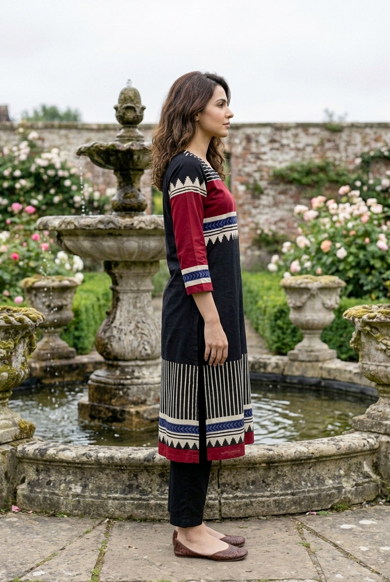 Side profile of woman in black, red, and blue tribal print kurta and black pants.