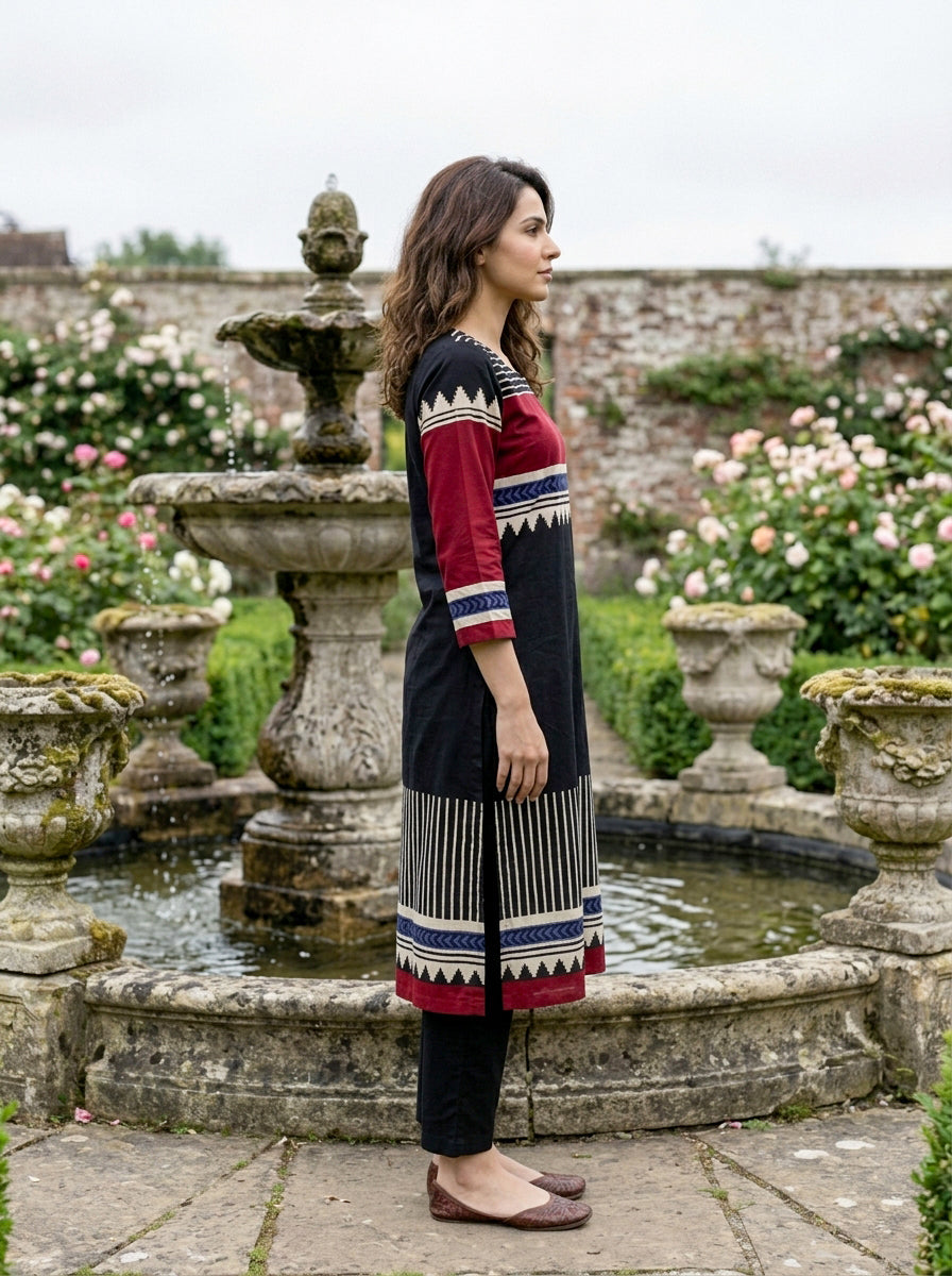Side profile of woman in black, red, and blue tribal print kurta and black pants.