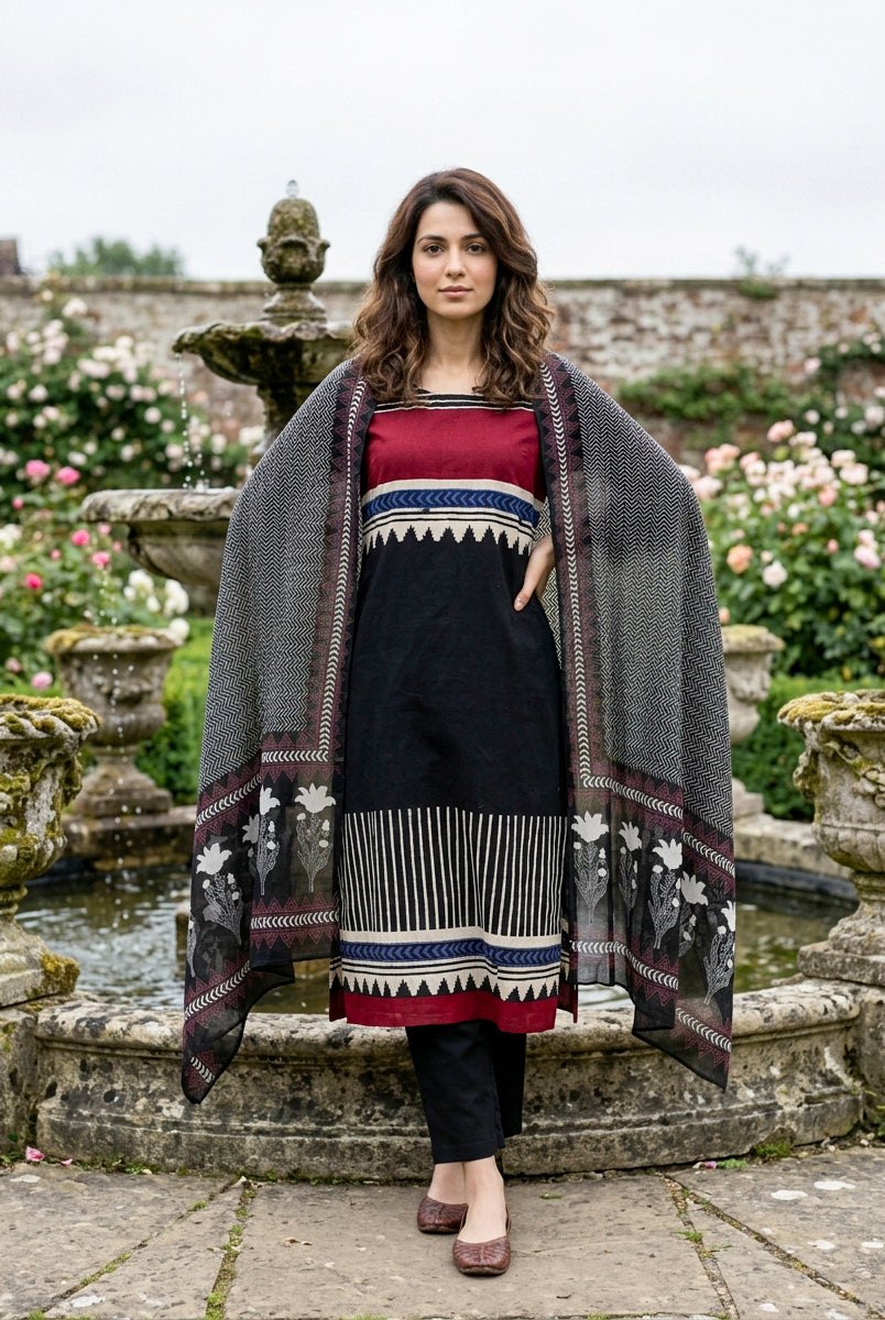 Model in front full look wearing black tribal print kurta set with red and patterned dupatta.