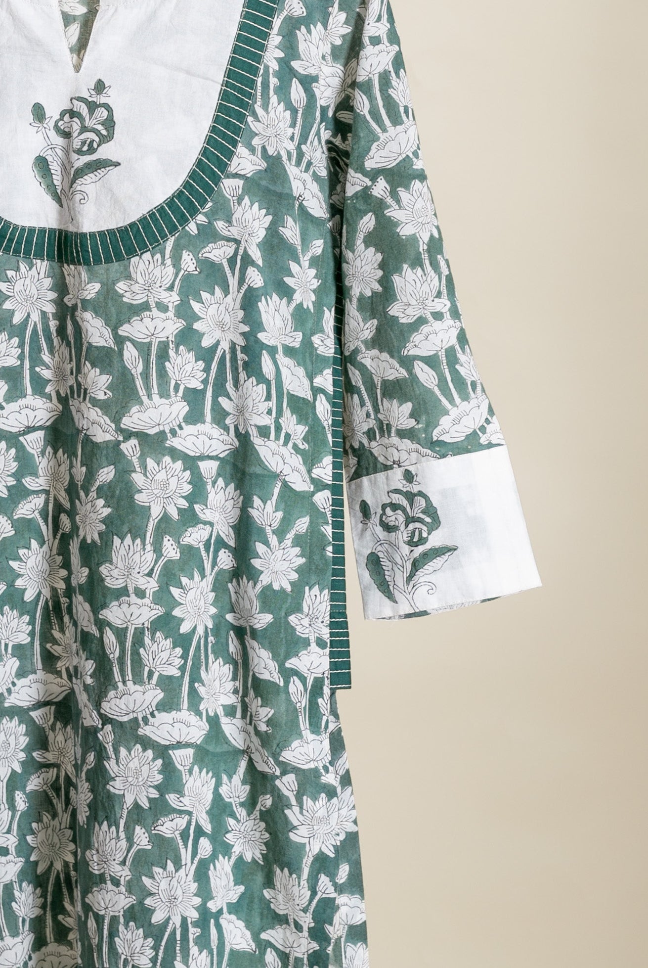 Close-up of flat sage green hand block print kurta with white lotus motifs.