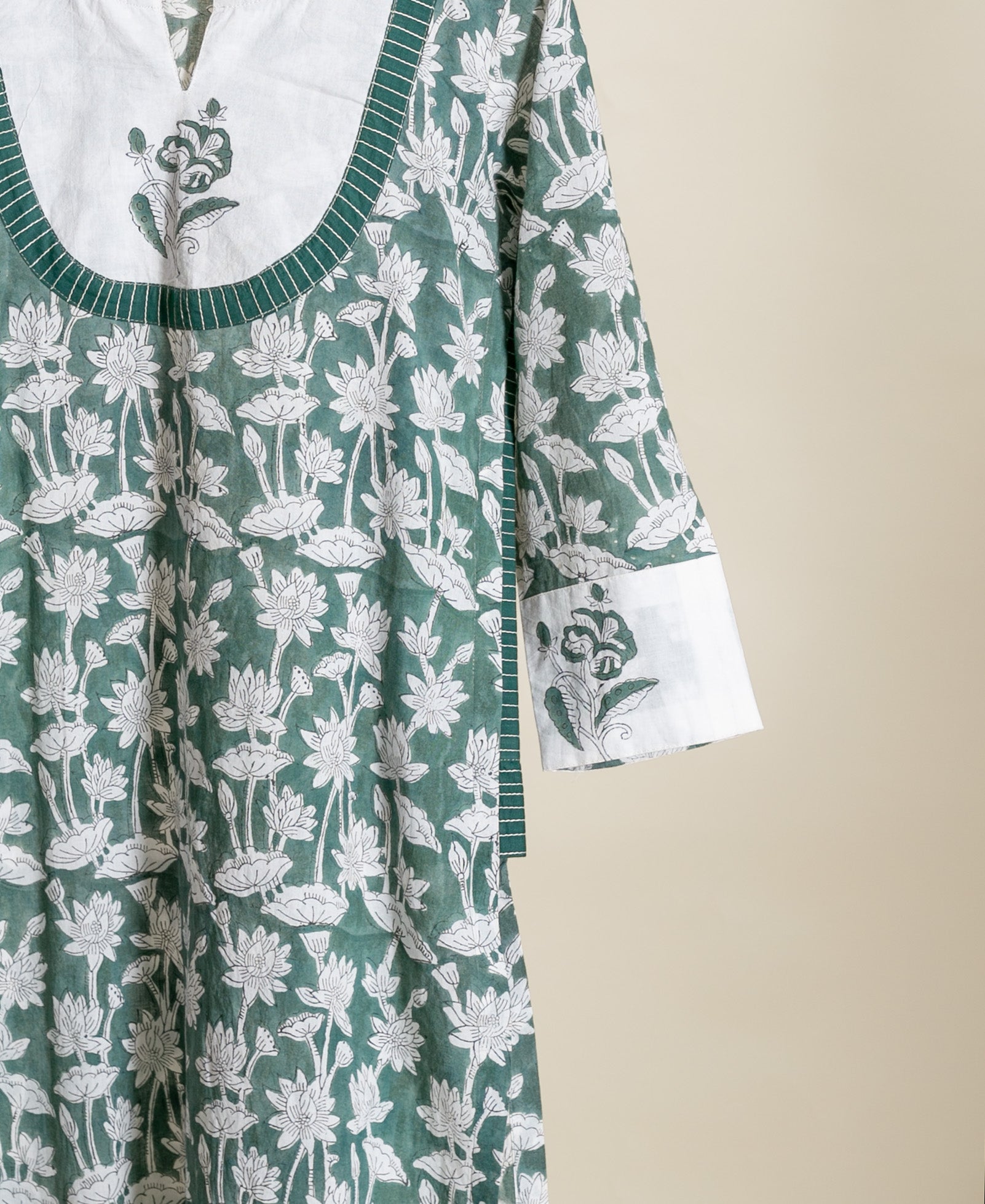 Close-up of flat sage green hand block print kurta with white lotus motifs.