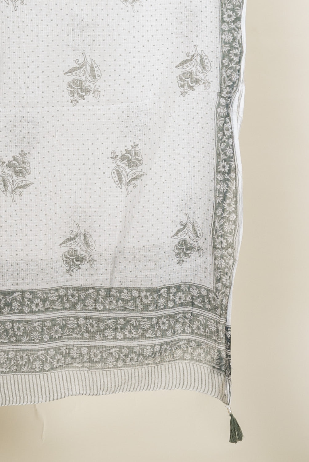 Draped off-white fabric with sage green floral, dotted, and border hand block print.