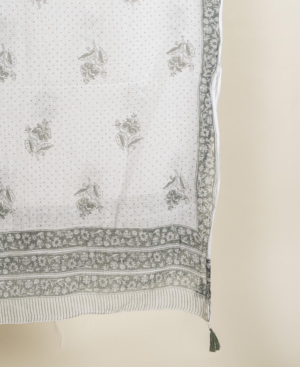 Draped off-white fabric with sage green floral, dotted, and border hand block print.