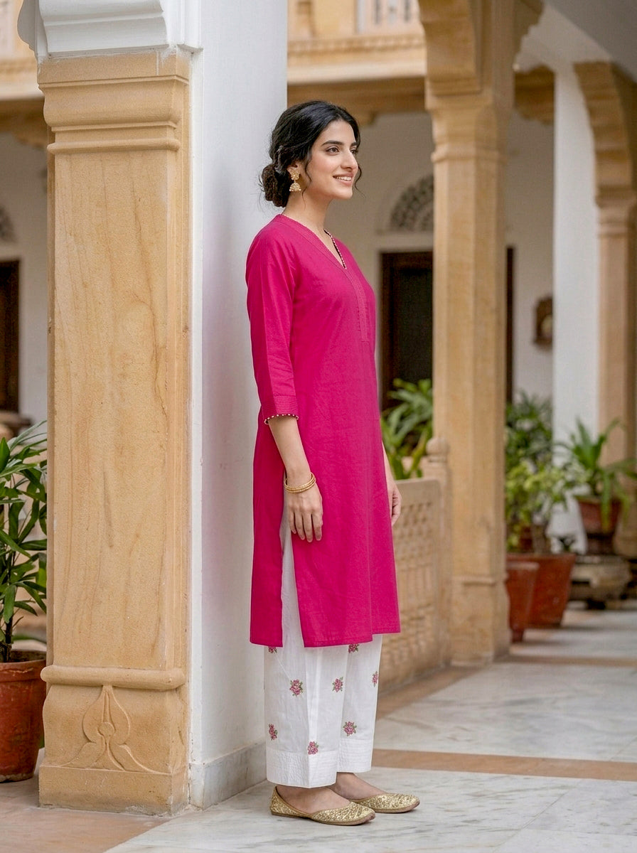 Side view of smiling model wearing fuchsia pink cotton kurta and white embroidered salwar.