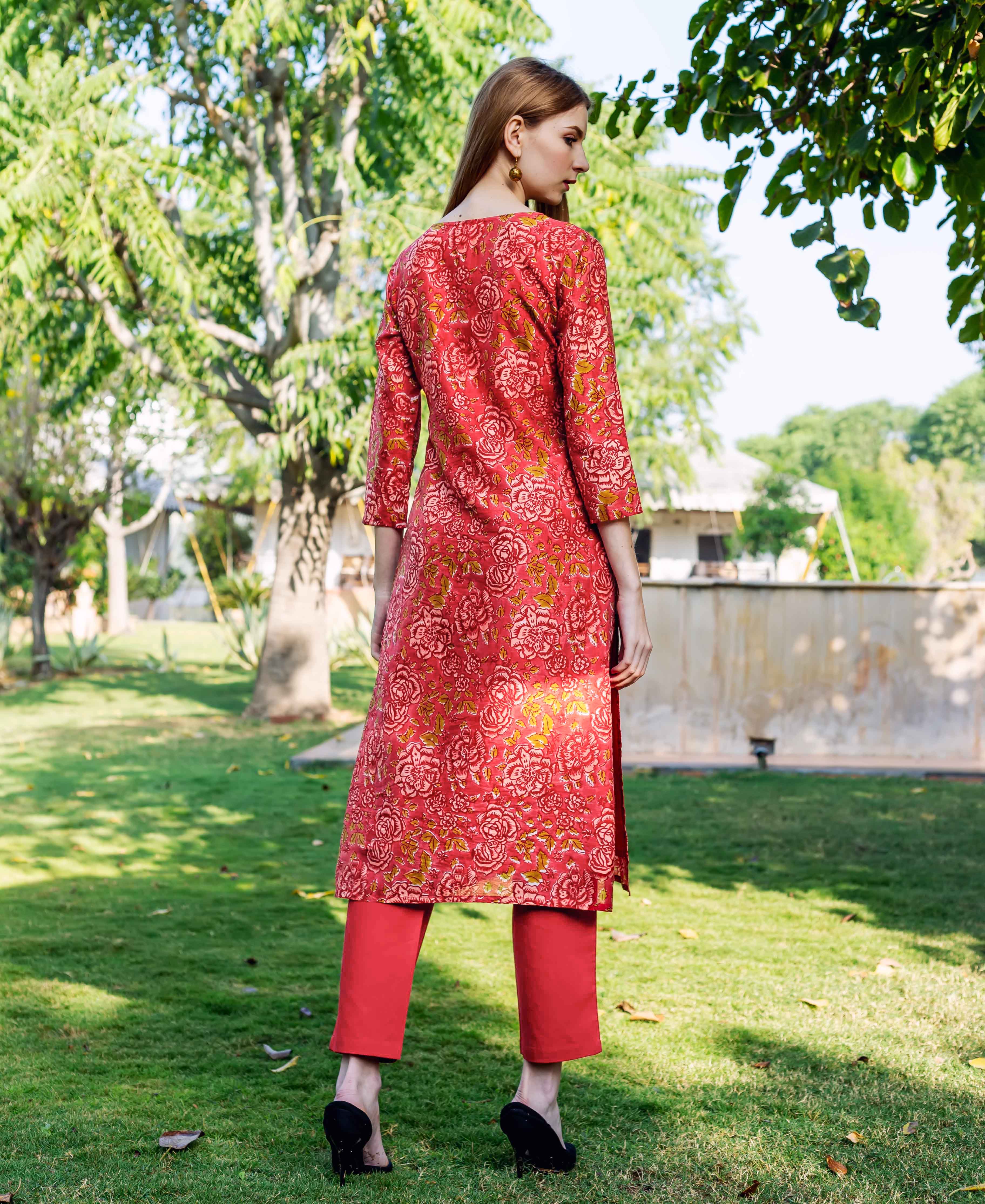 Rear view of a model wearing a red floral hand-block-printed straight kurta with red pants.
