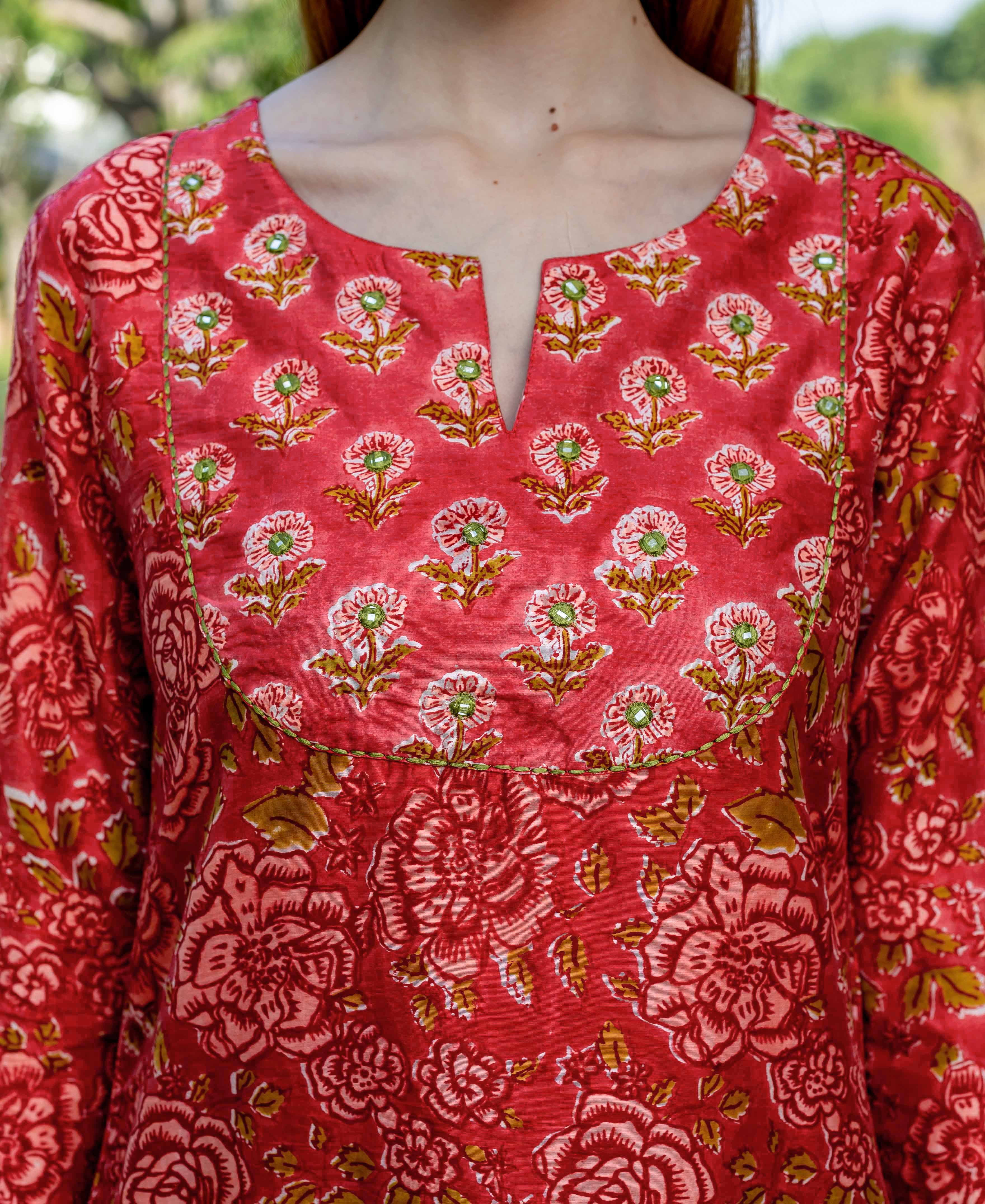 Red hand-block printed kurta on model, with floral patterns and a mirror-embroidered notched neckline.