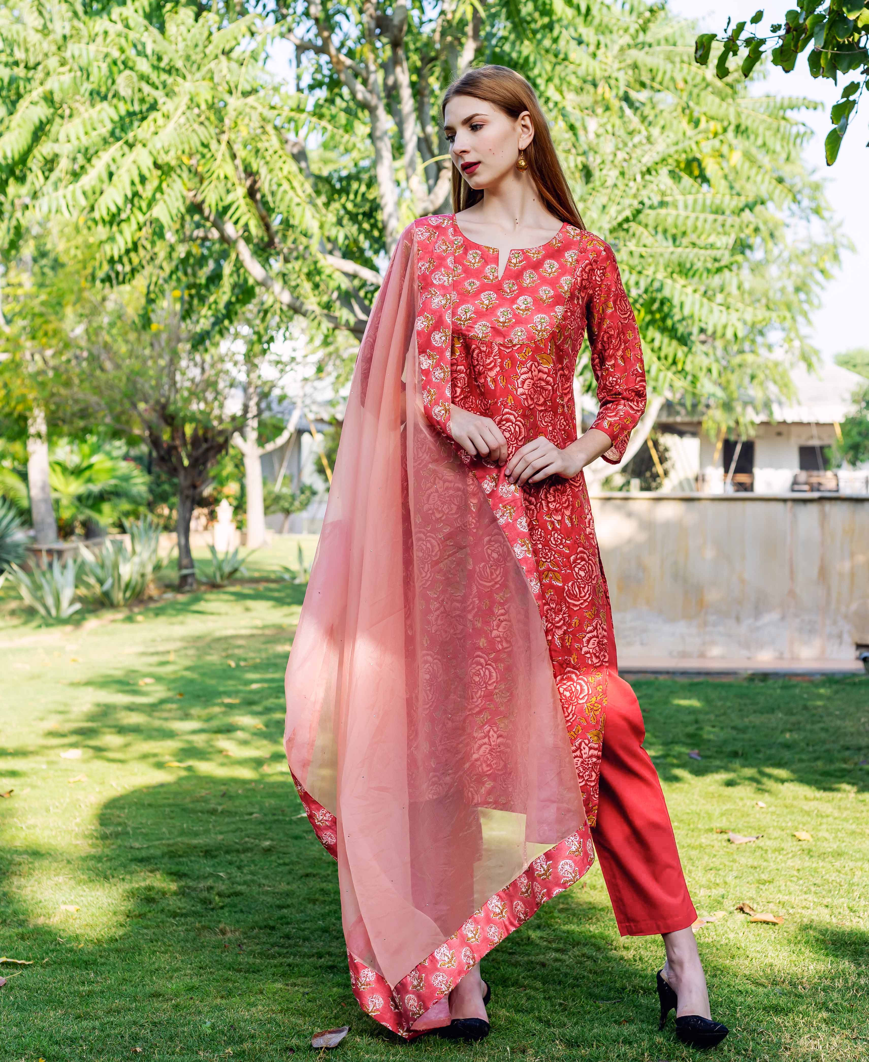 Full-length model wears a vibrant red floral print kurta set with a sheer dupatta.