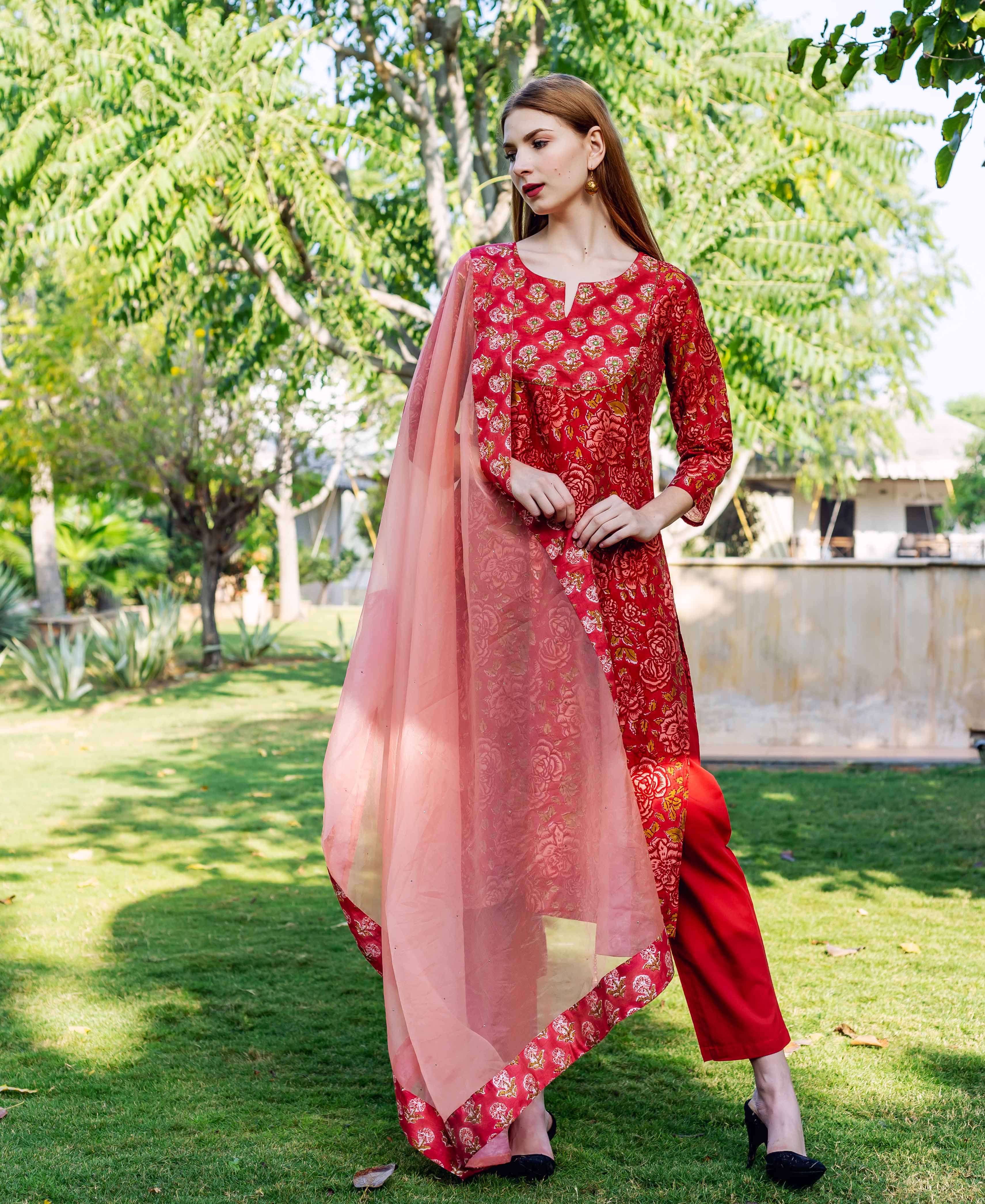A model wearing a red and gold floral print kurta with a peach organza dupatta.