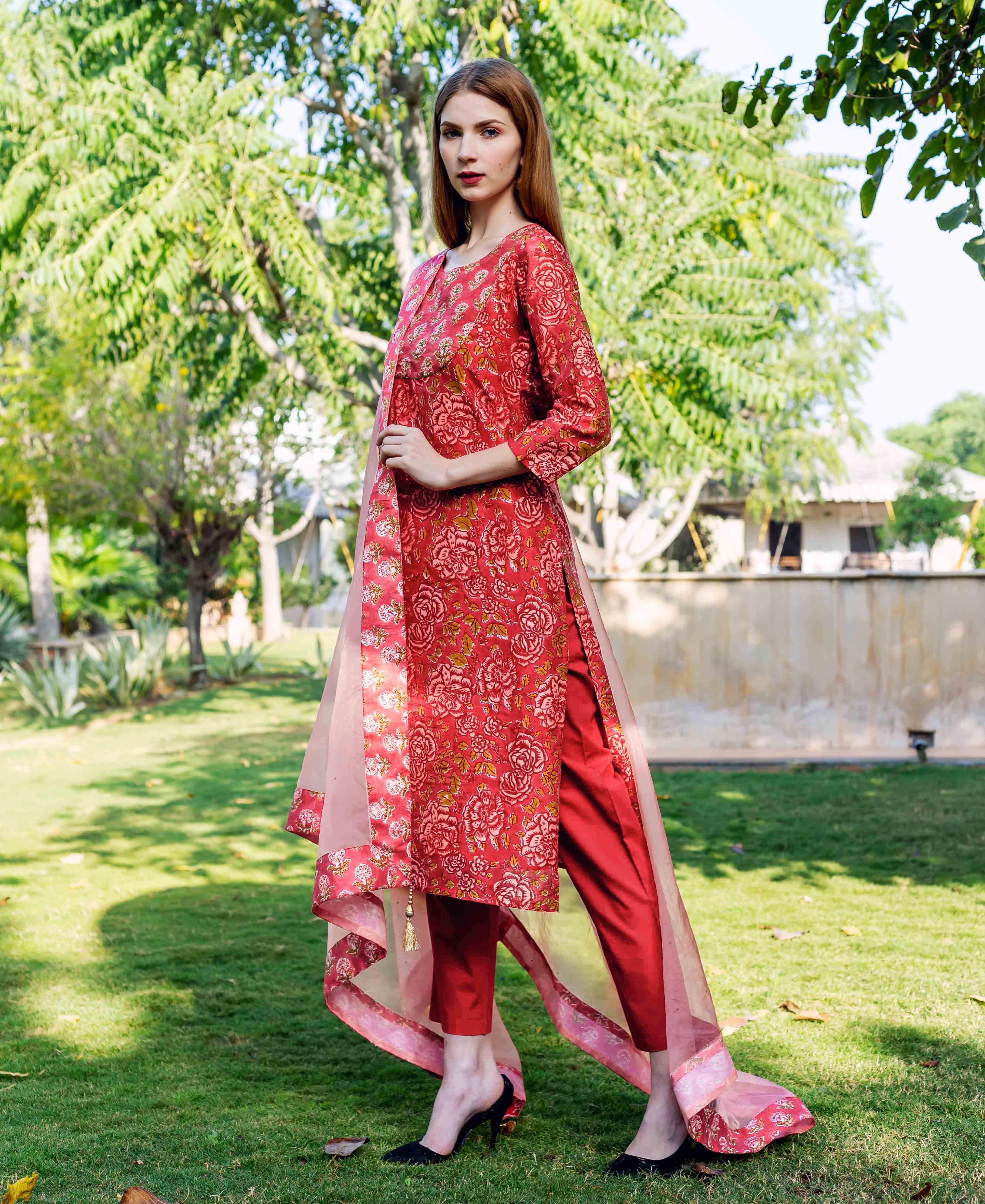 Model wears a red hand-block-printed floral straight kurta set with sheer dupatta.