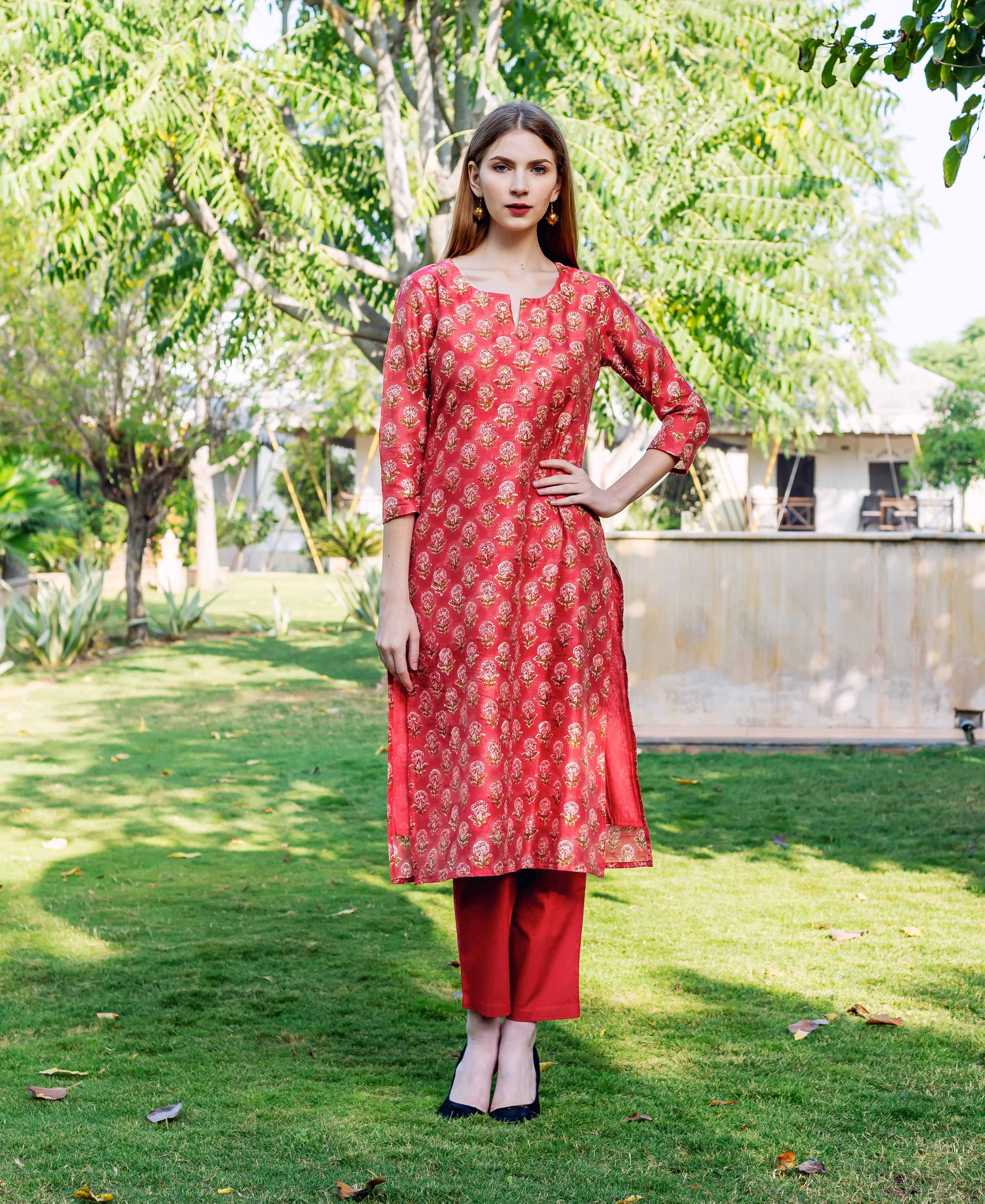 Female model standing in a red hand-block printed straight kurta and matching trousers.