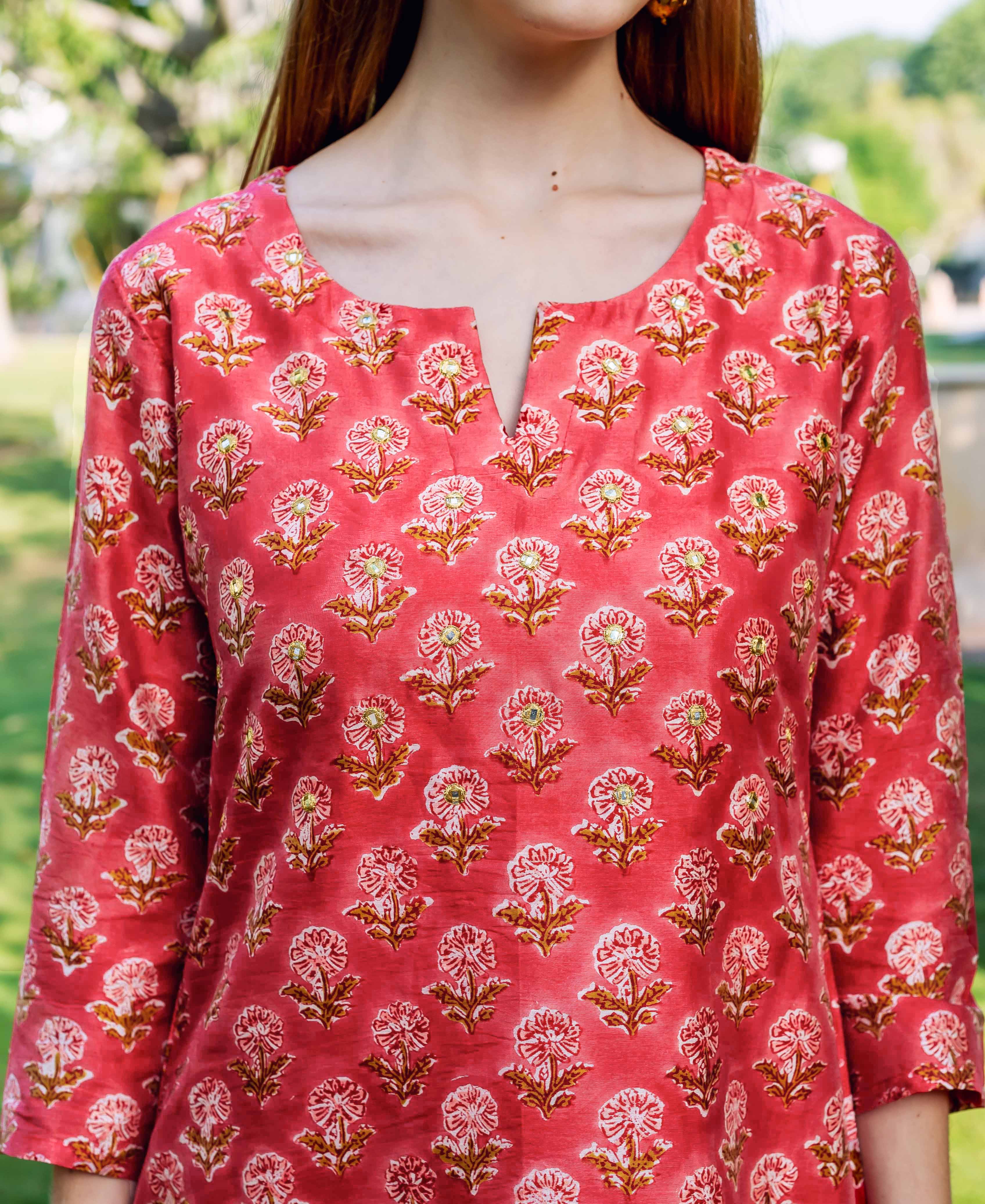 Close-up of a model wearing a red hand-block printed kurta with white and golden floral pattern.