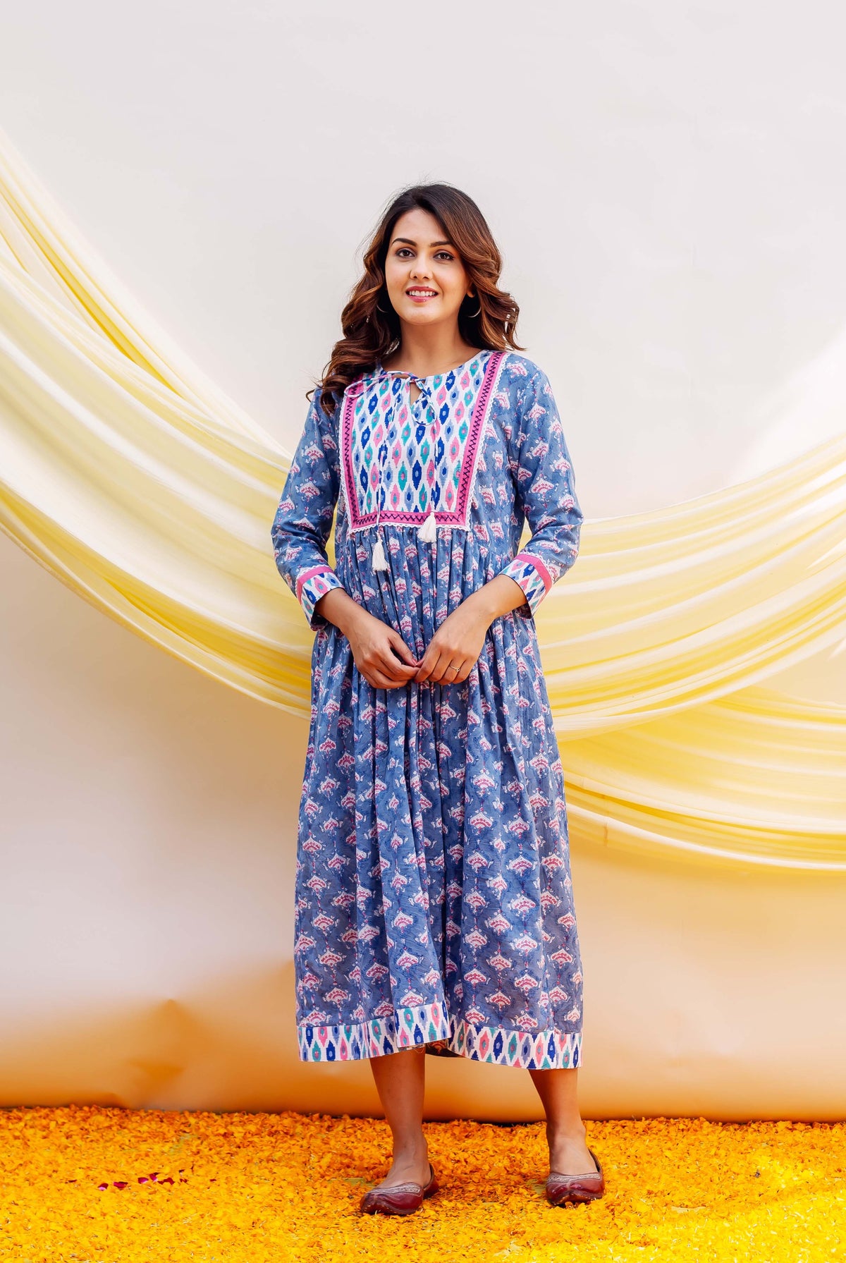 Blue block-printed midi dress with pink geometric yoke on a smiling woman.