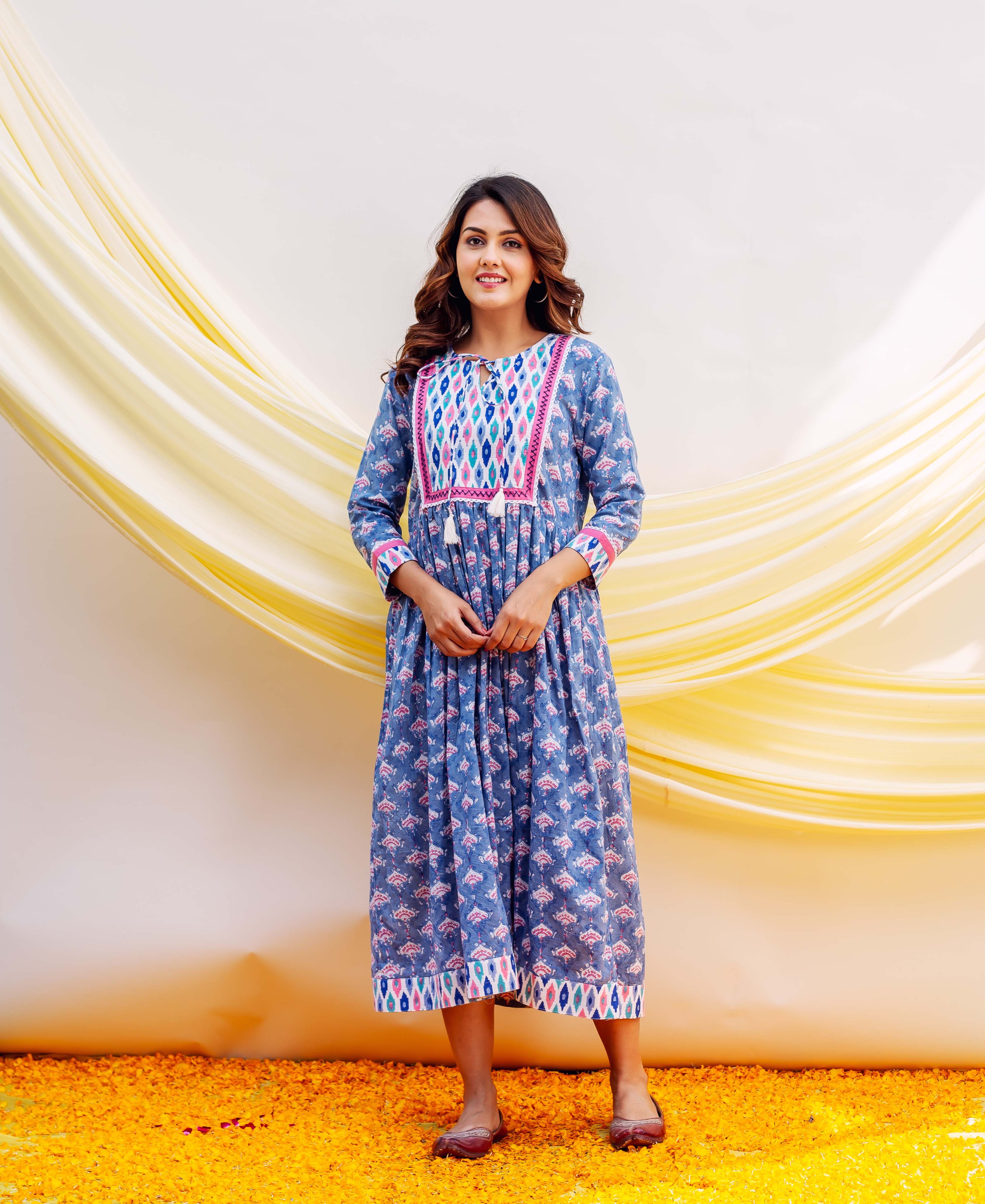 Blue block-printed midi dress with pink geometric yoke on a smiling woman.