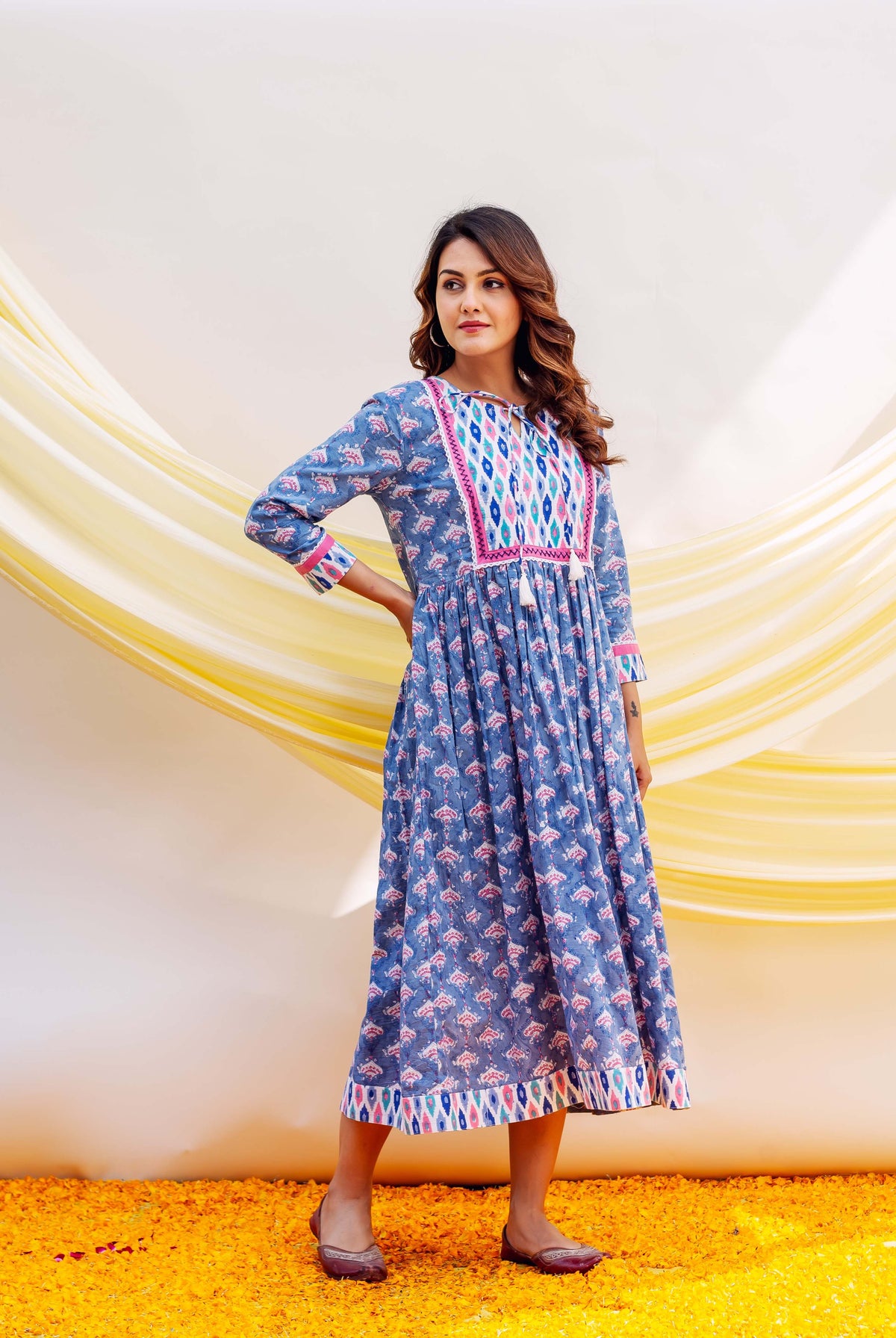 Woman in blue midi dress with small pink print and a vibrant multi-colored geometric yoke.