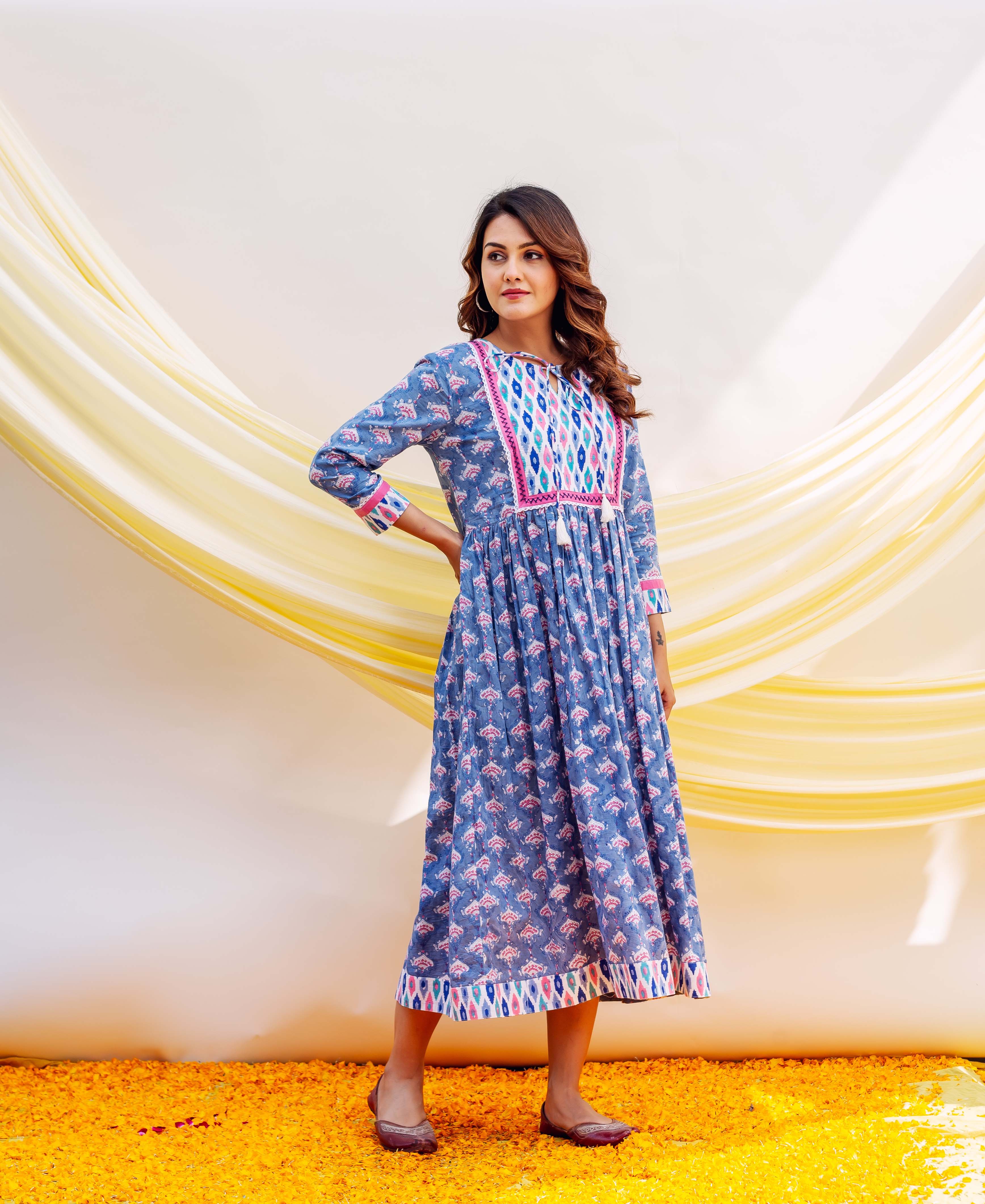 Woman in blue midi dress with small pink print and a vibrant multi-colored geometric yoke.