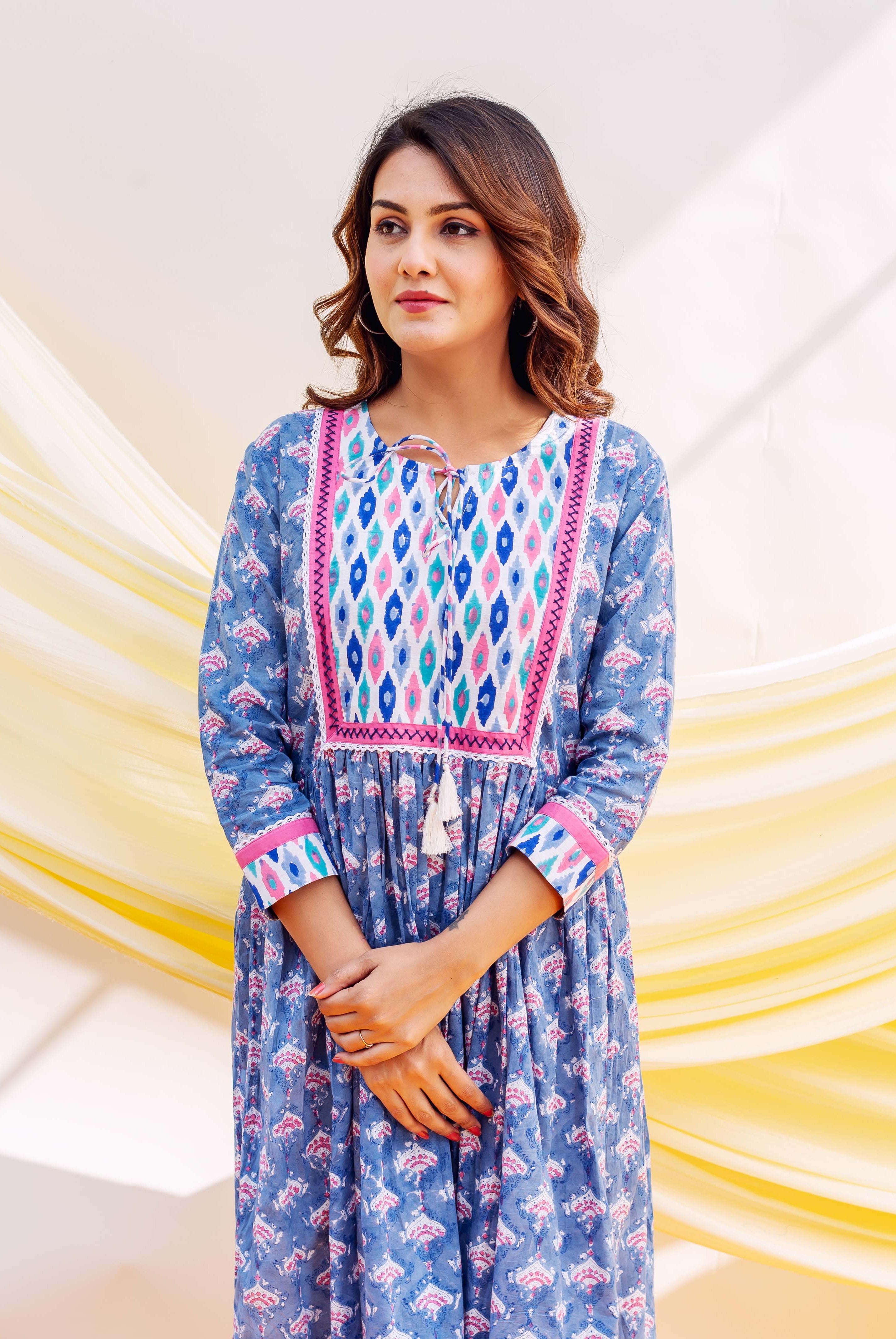 Woman in a blue block-printed dress featuring a pink and blue geometric patterned yoke.