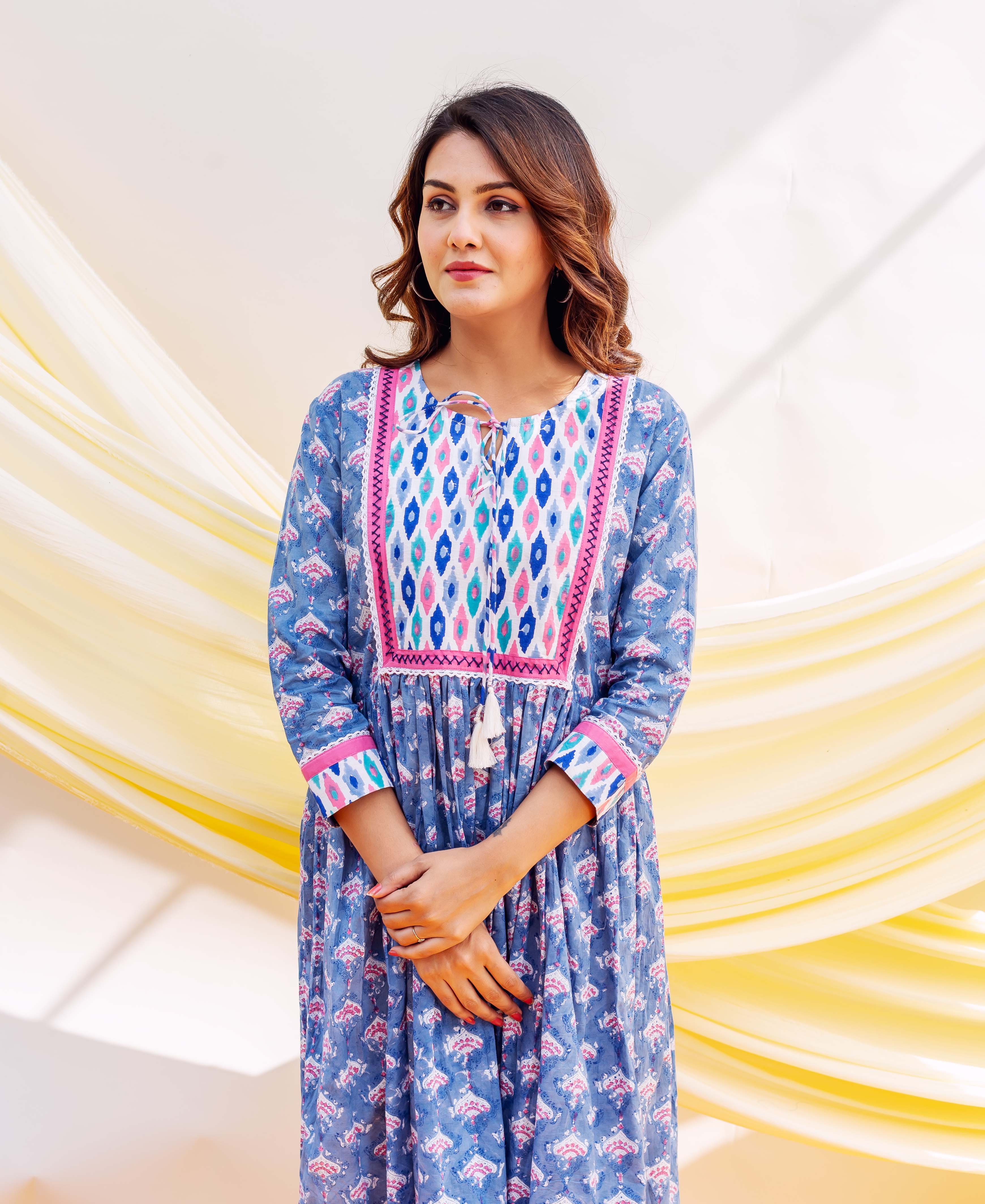 Woman in a blue block-printed dress featuring a pink and blue geometric patterned yoke.