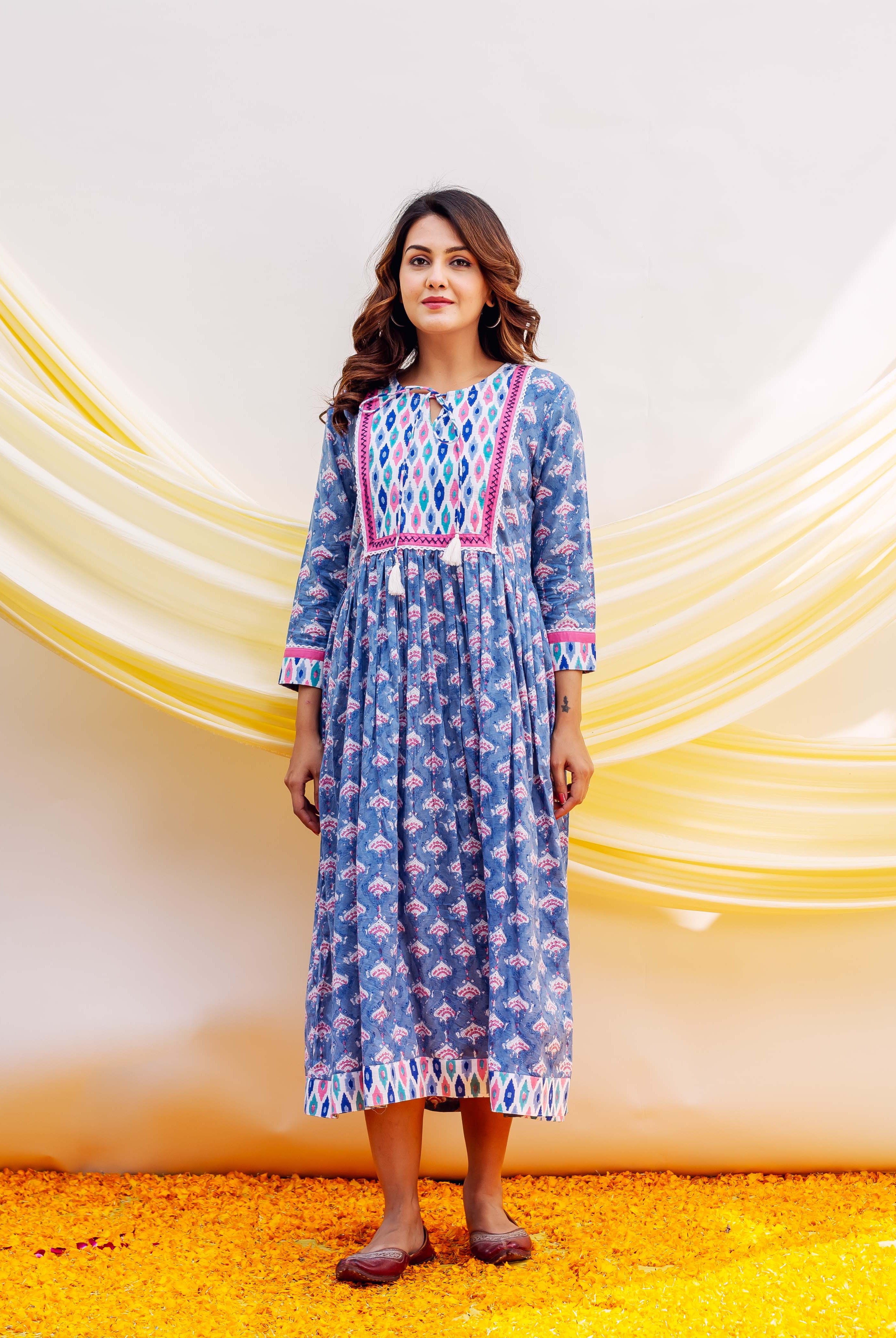 Full shot of a woman in a blue block-printed cotton dress with vibrant pink patterns.