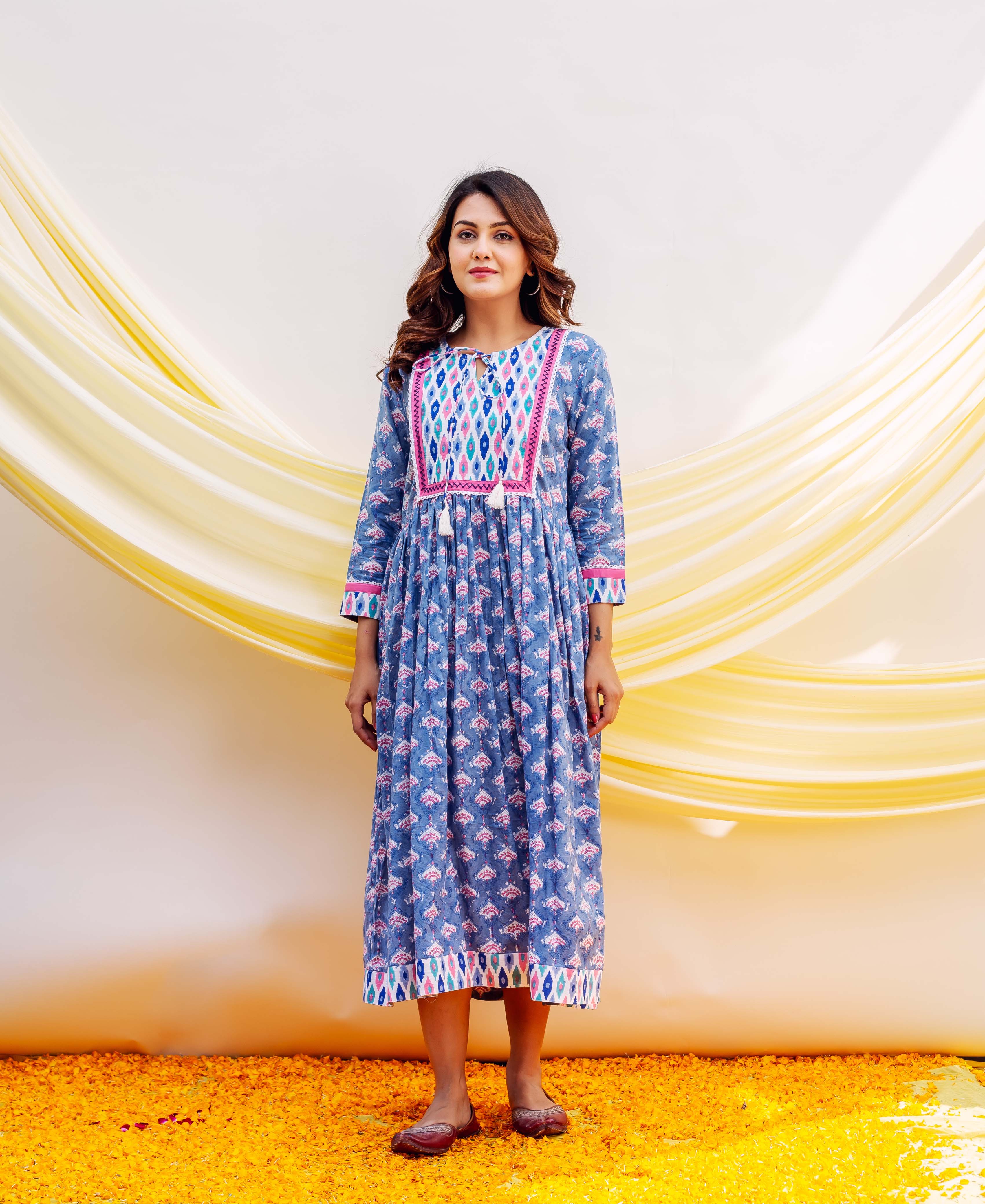 Full shot of a woman in a blue block-printed cotton dress with vibrant pink patterns.