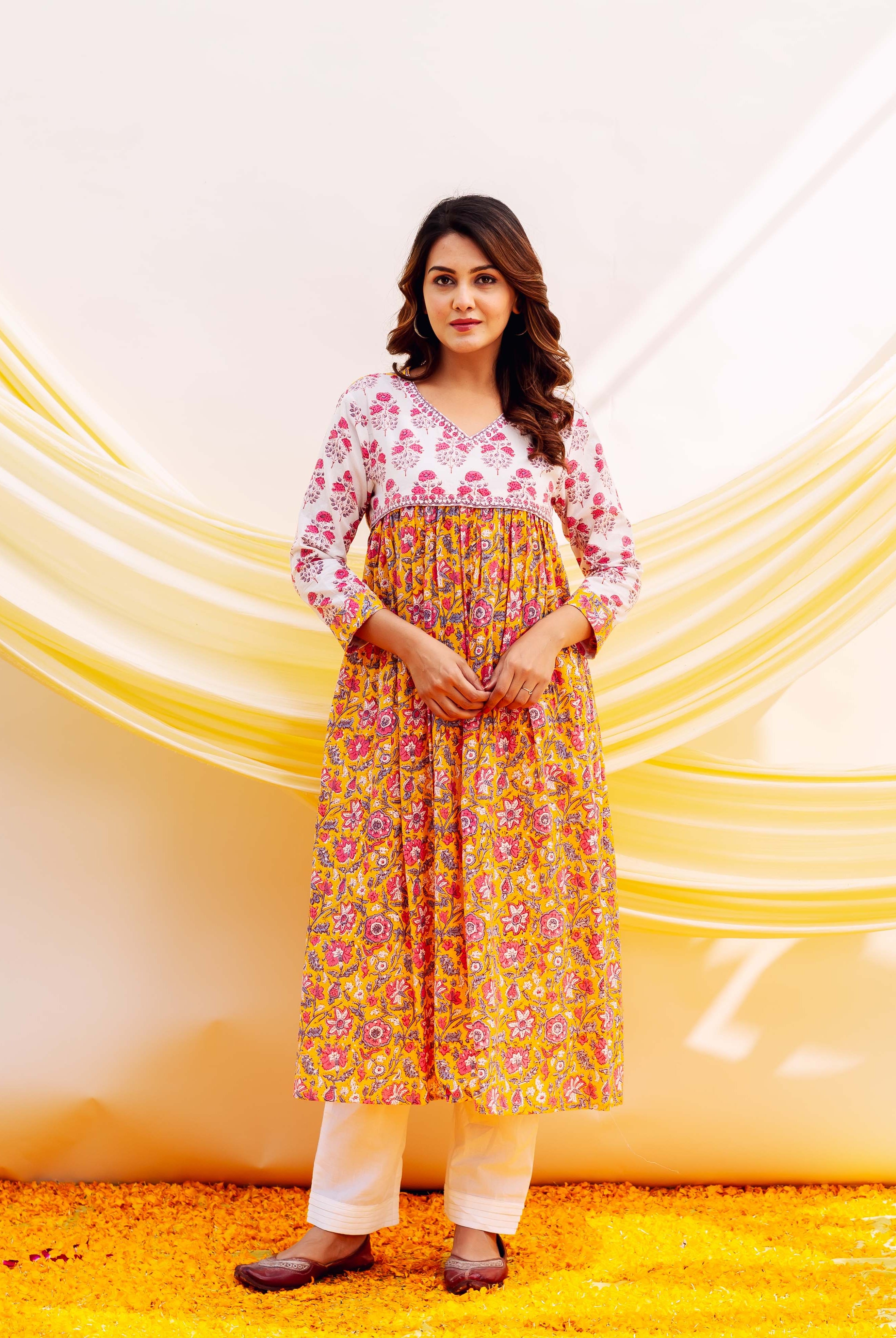 Front view of model wearing a yellow and white floral hand-block printed kurta with white pants.