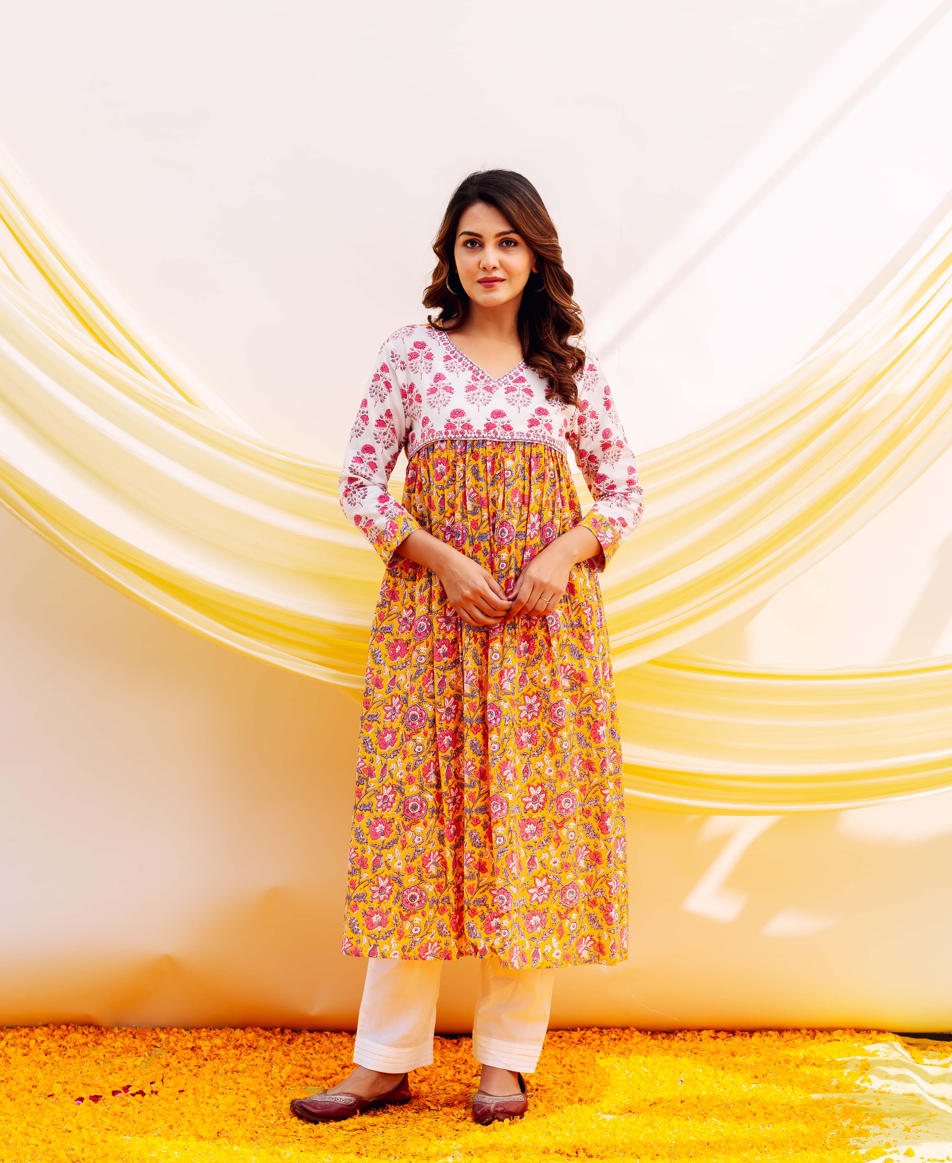 Front view of model wearing a yellow and white floral hand-block printed kurta with white pants.