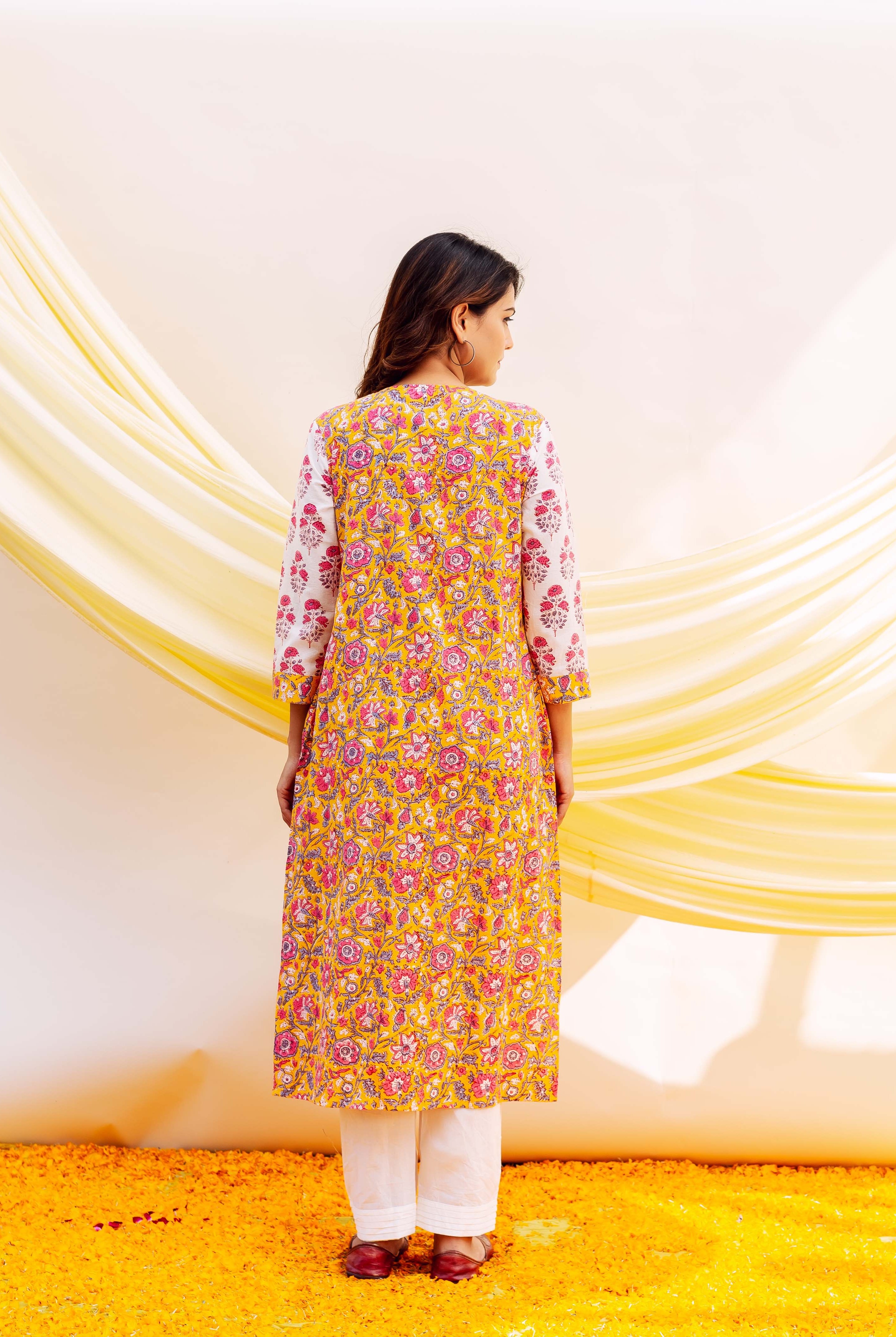 Back view of model wearing a long yellow hand-block printed cotton kurta with pink florals.