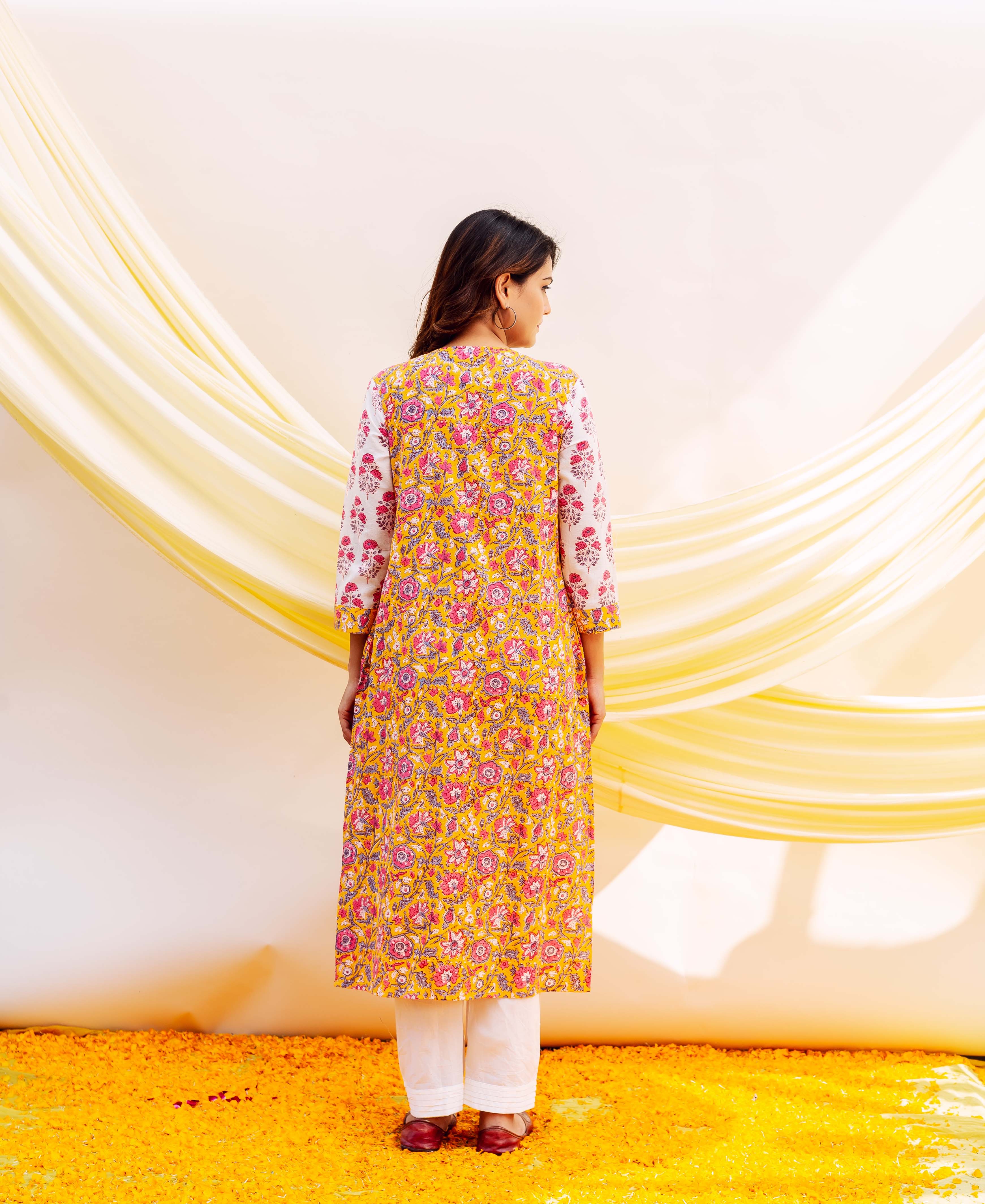Back view of model wearing a long yellow hand-block printed cotton kurta with pink florals.