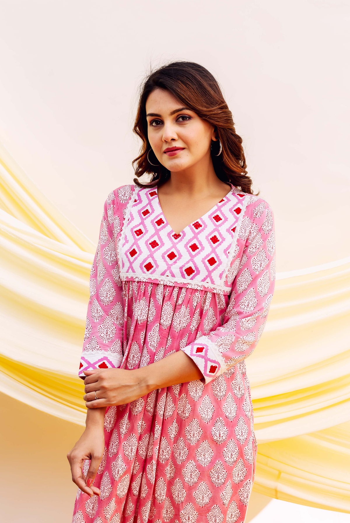 Woman wearing pink block-printed kurta with white and red geometric patterns and floral designs.