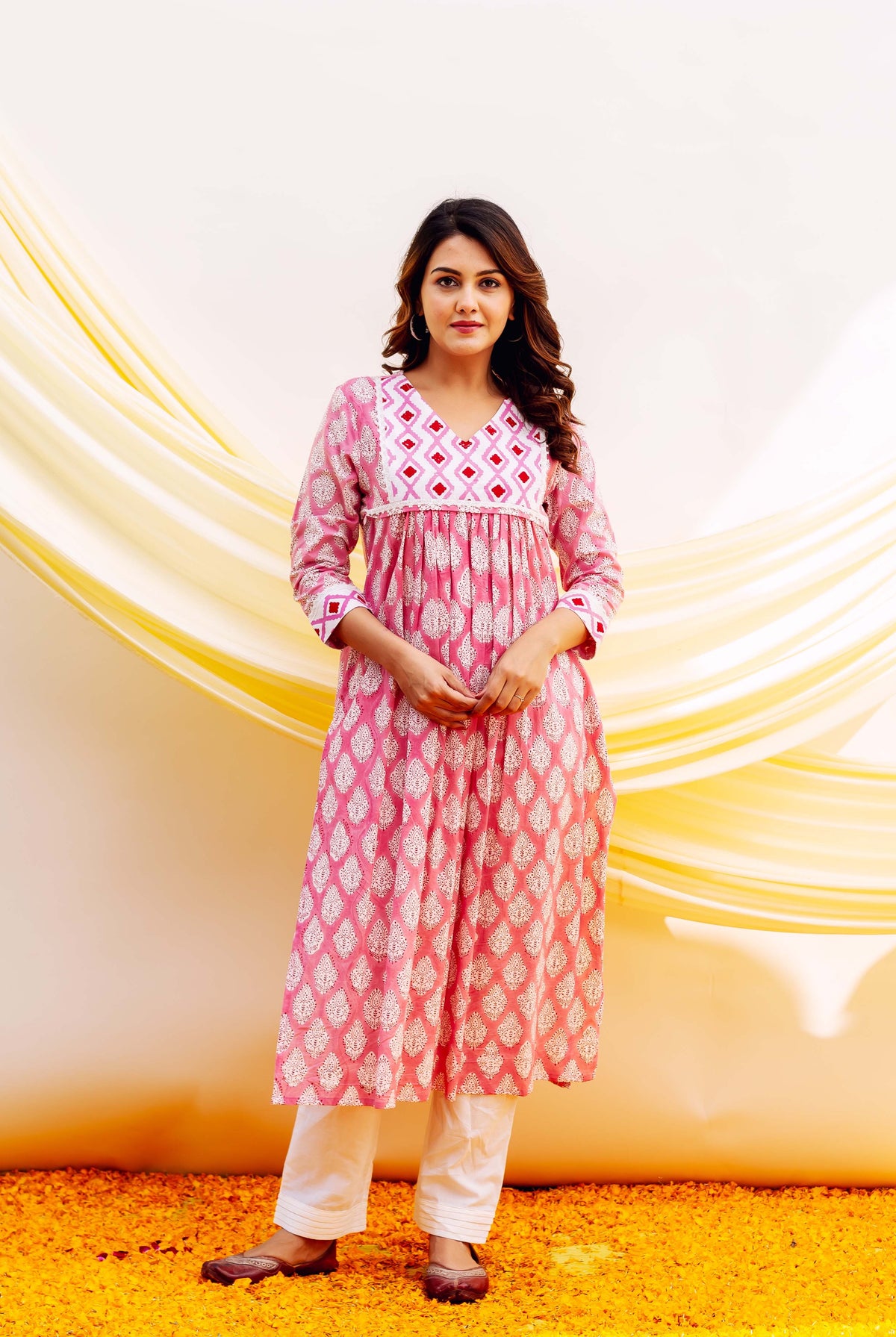 Woman wearing pink and white patterned hand-block-printed cotton nursing kurt a with white pants.