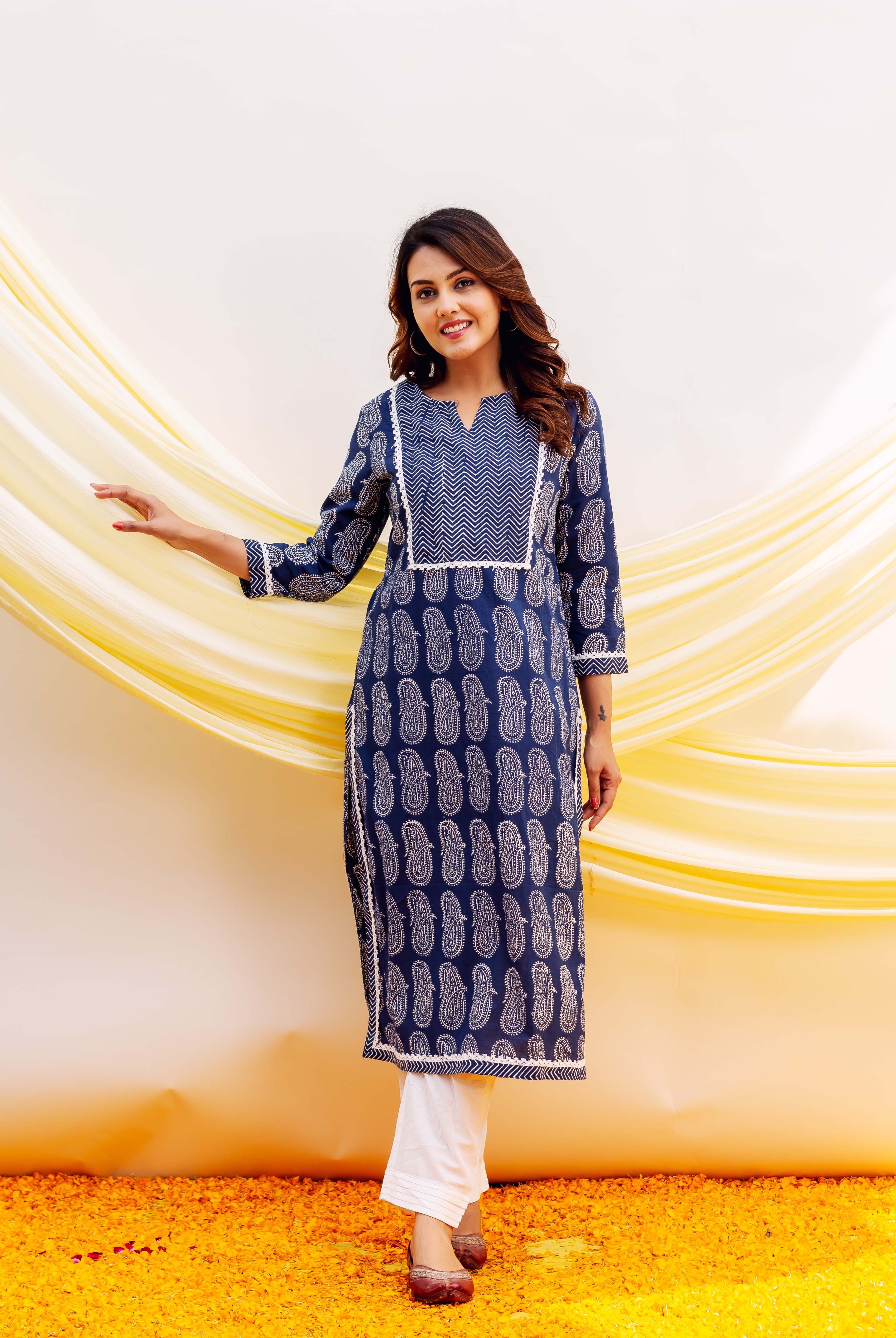 Model wearing a full-length navy blue block-printed paisley kurta with white chevron yoke and white bottoms.
