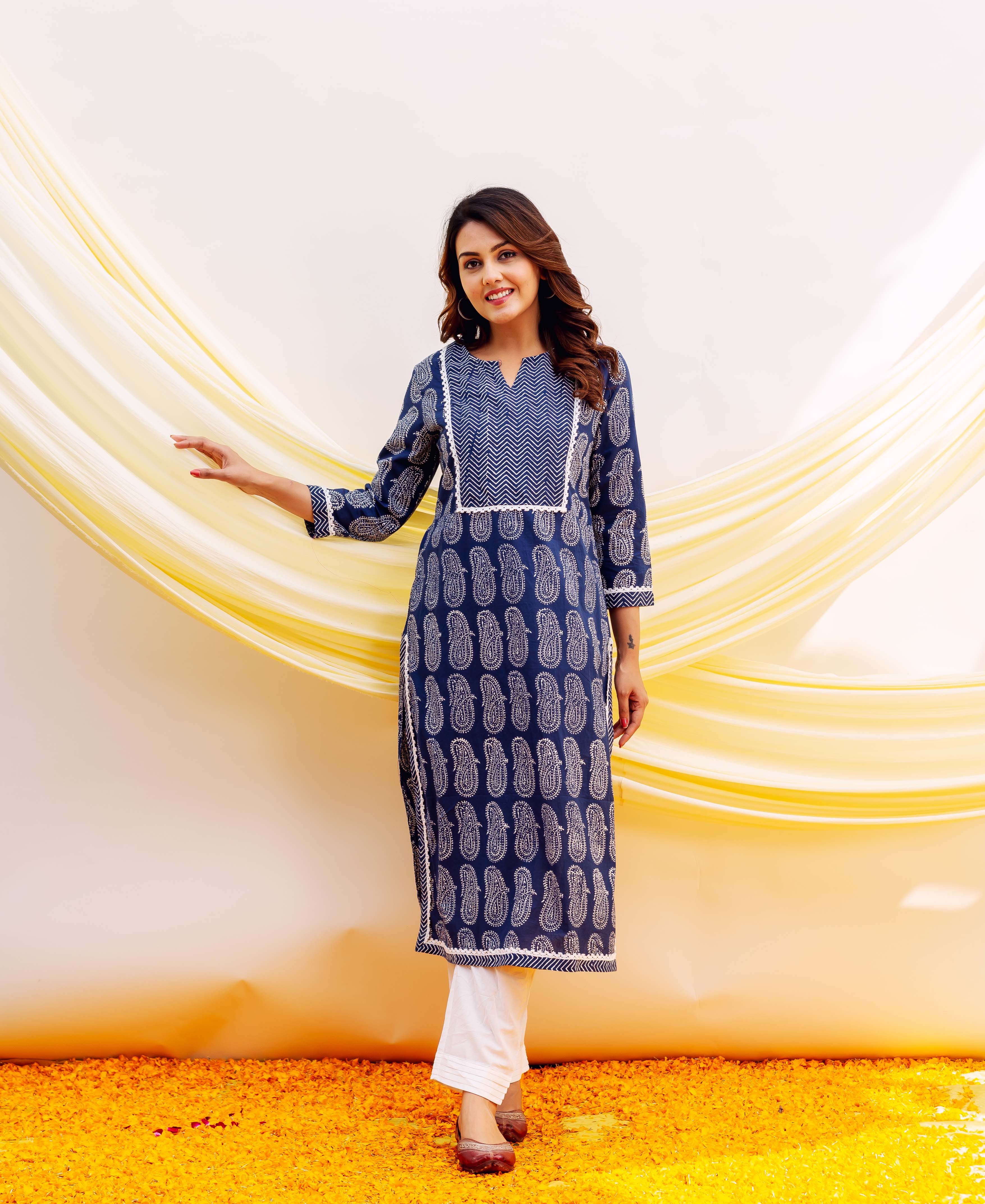 Model wearing a full-length navy blue block-printed paisley kurta with white chevron yoke and white bottoms.
