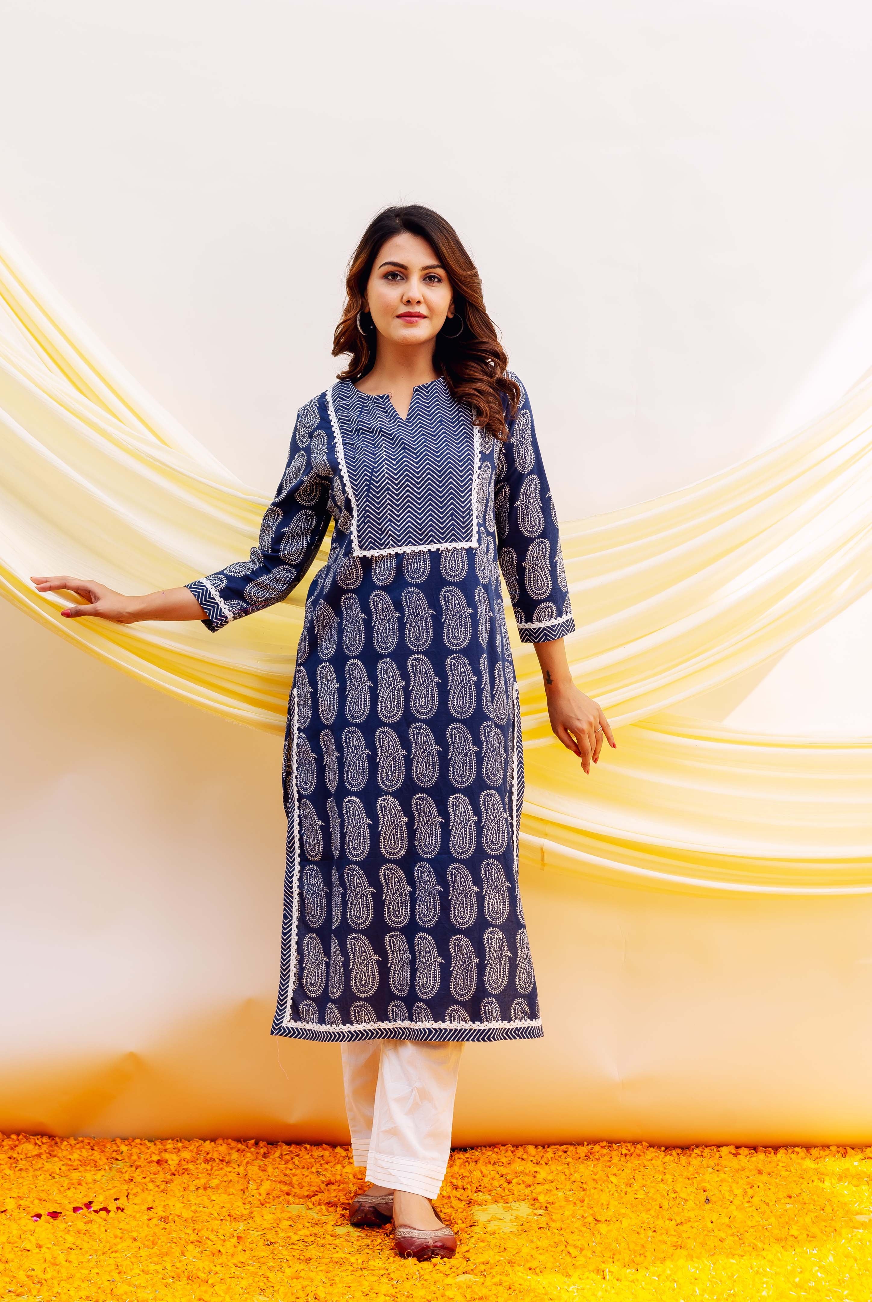 Full-length woman wearing navy blue hand-block printed kurta with white paisley and chevron patterns, white pants.