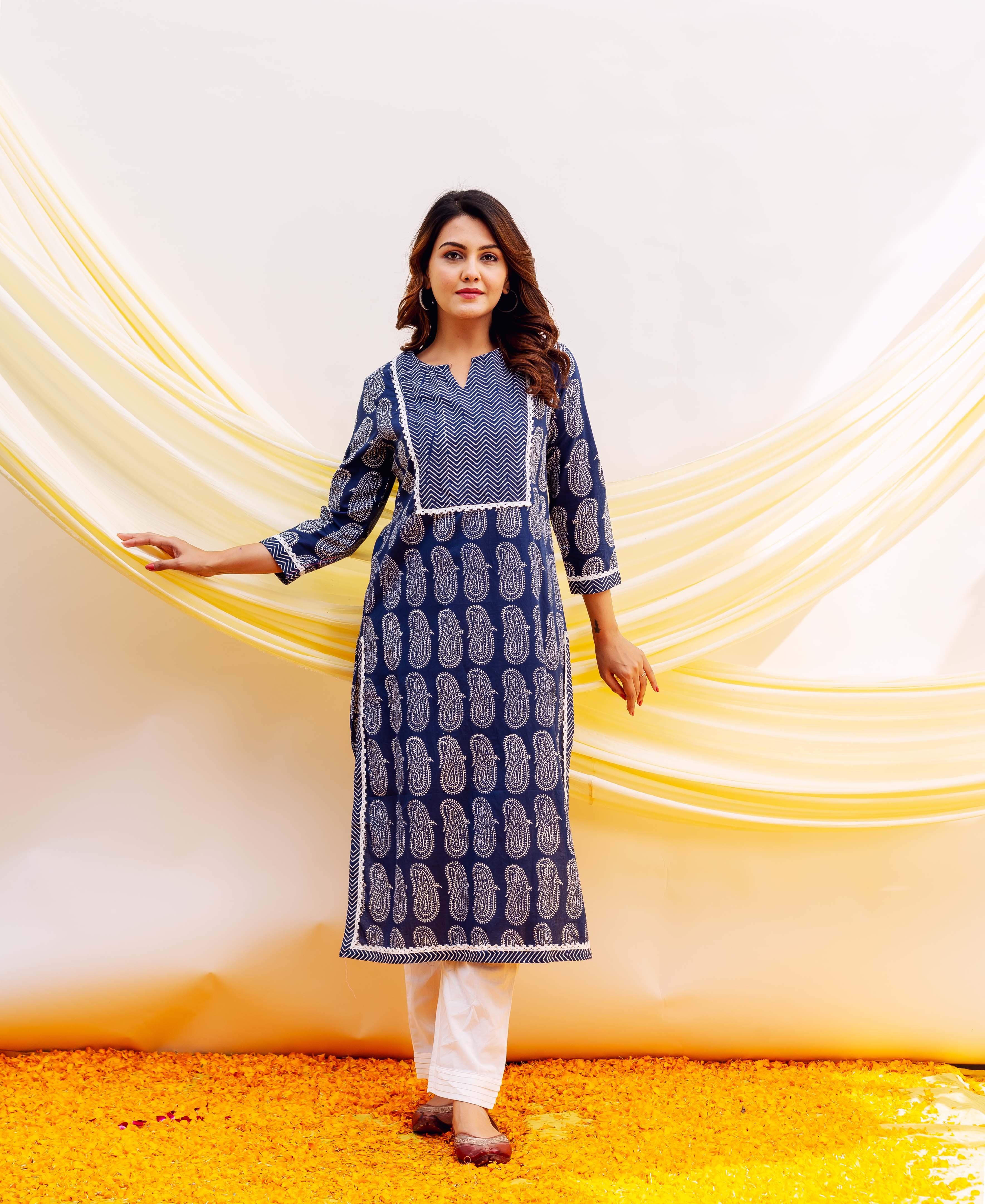 Full-length woman wearing navy blue hand-block printed kurta with white paisley and chevron patterns, white pants.