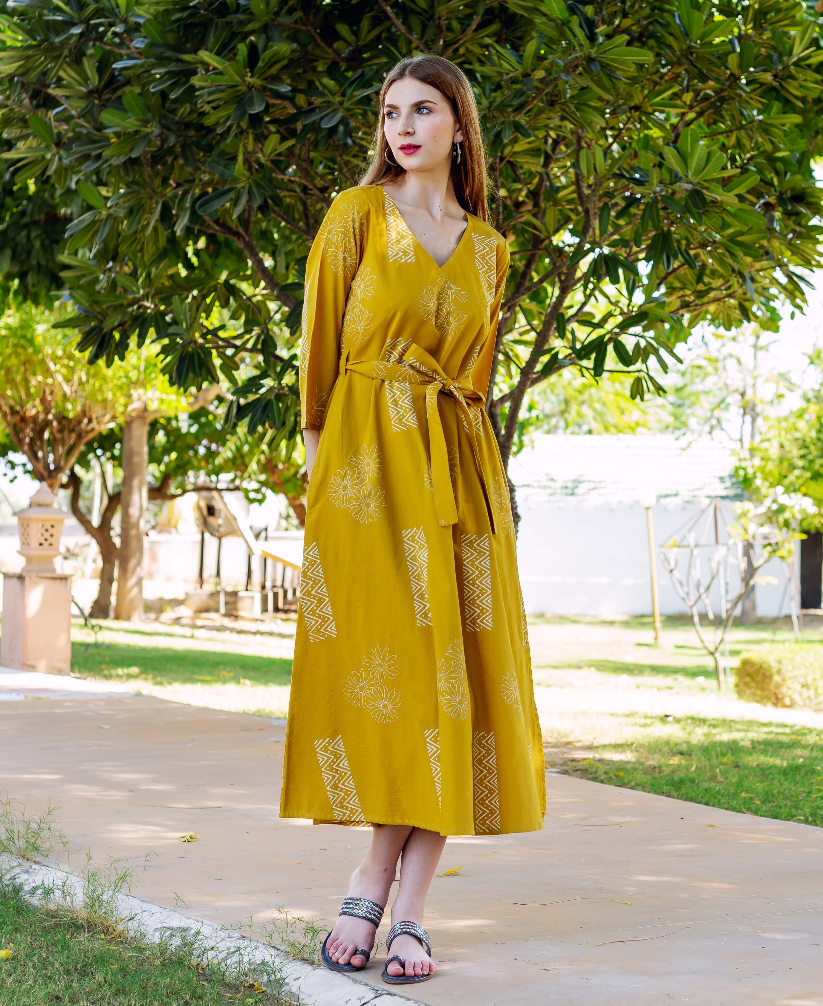 Model in mustard yellow V-neck dress with white hand-block-printed floral and geometric patterns.
