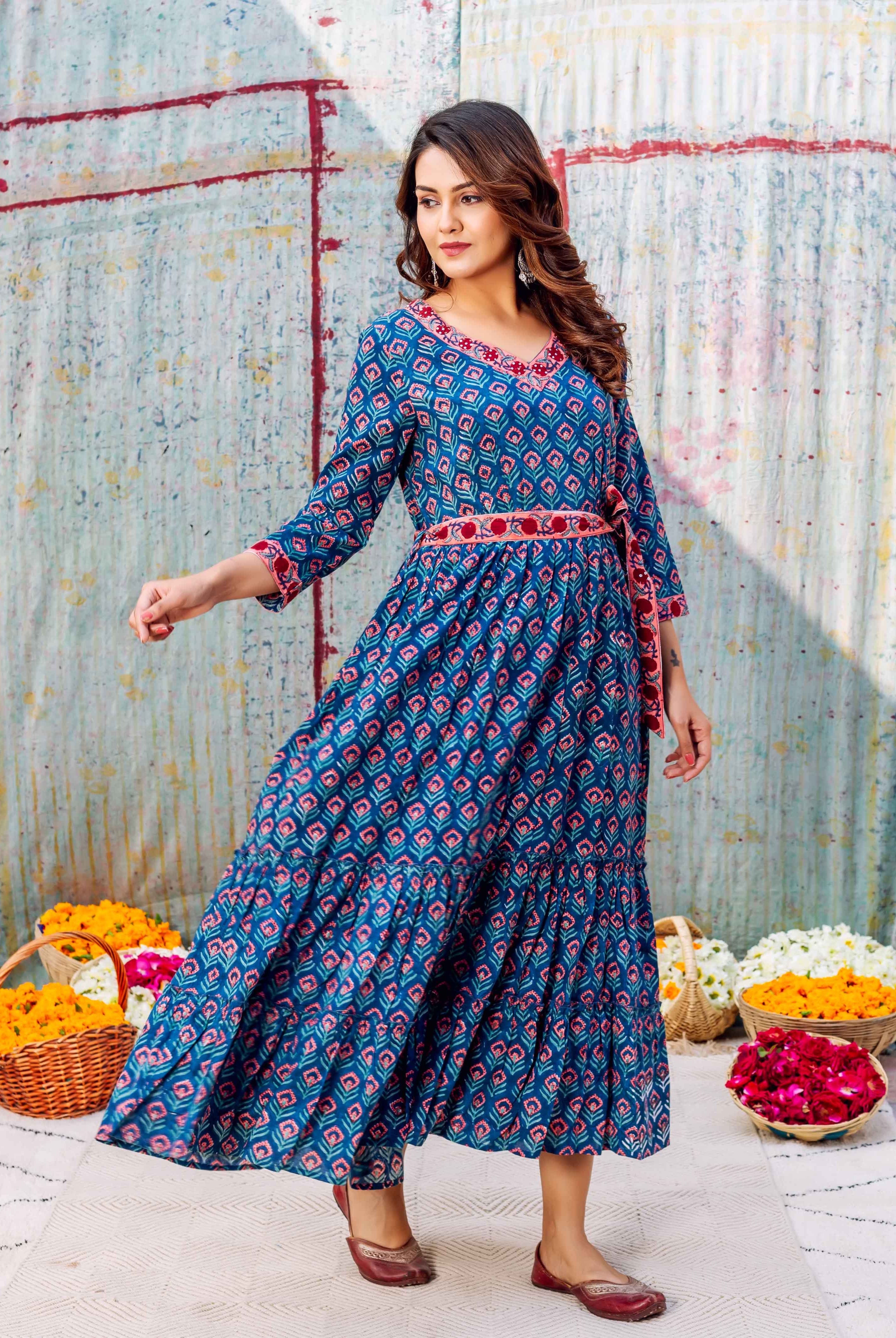 Model in azure full-length hand block printed dress, red geometric pattern, V-neck, tiered skirt.