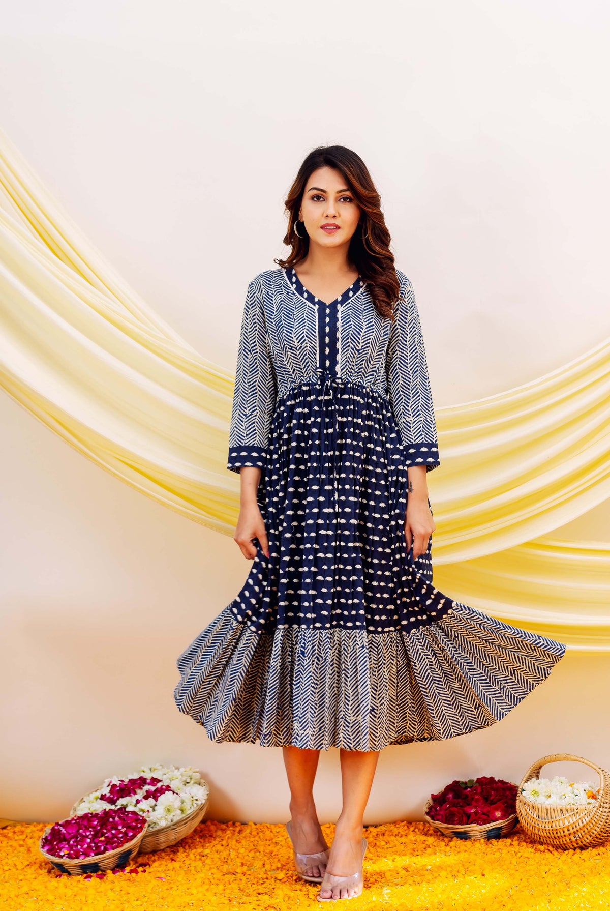 Front view of model in a flowing indigo blue and white block-printed tiered midi dress.