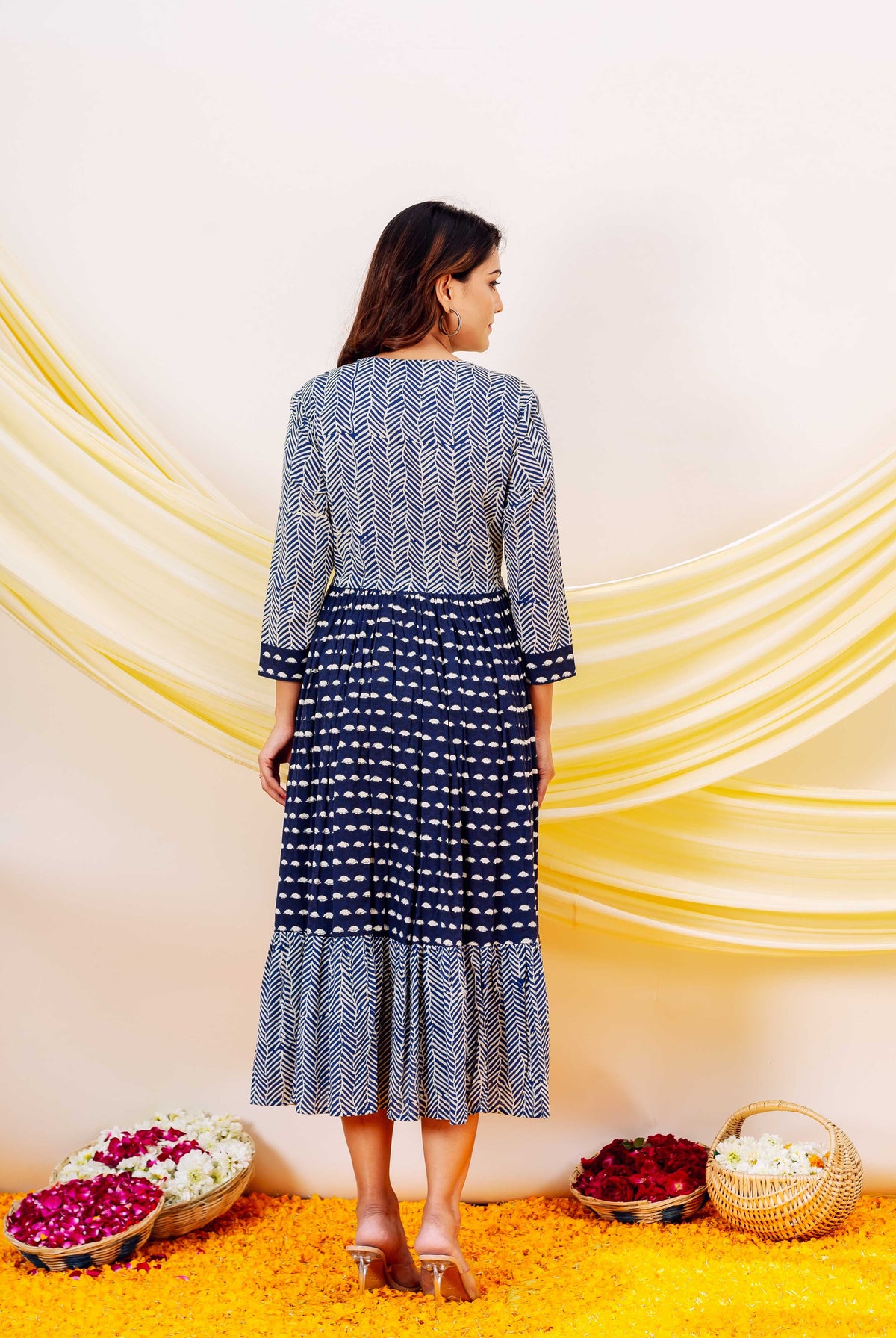 A model wearing a blue and white indigo printed dress with a ruffled hem.