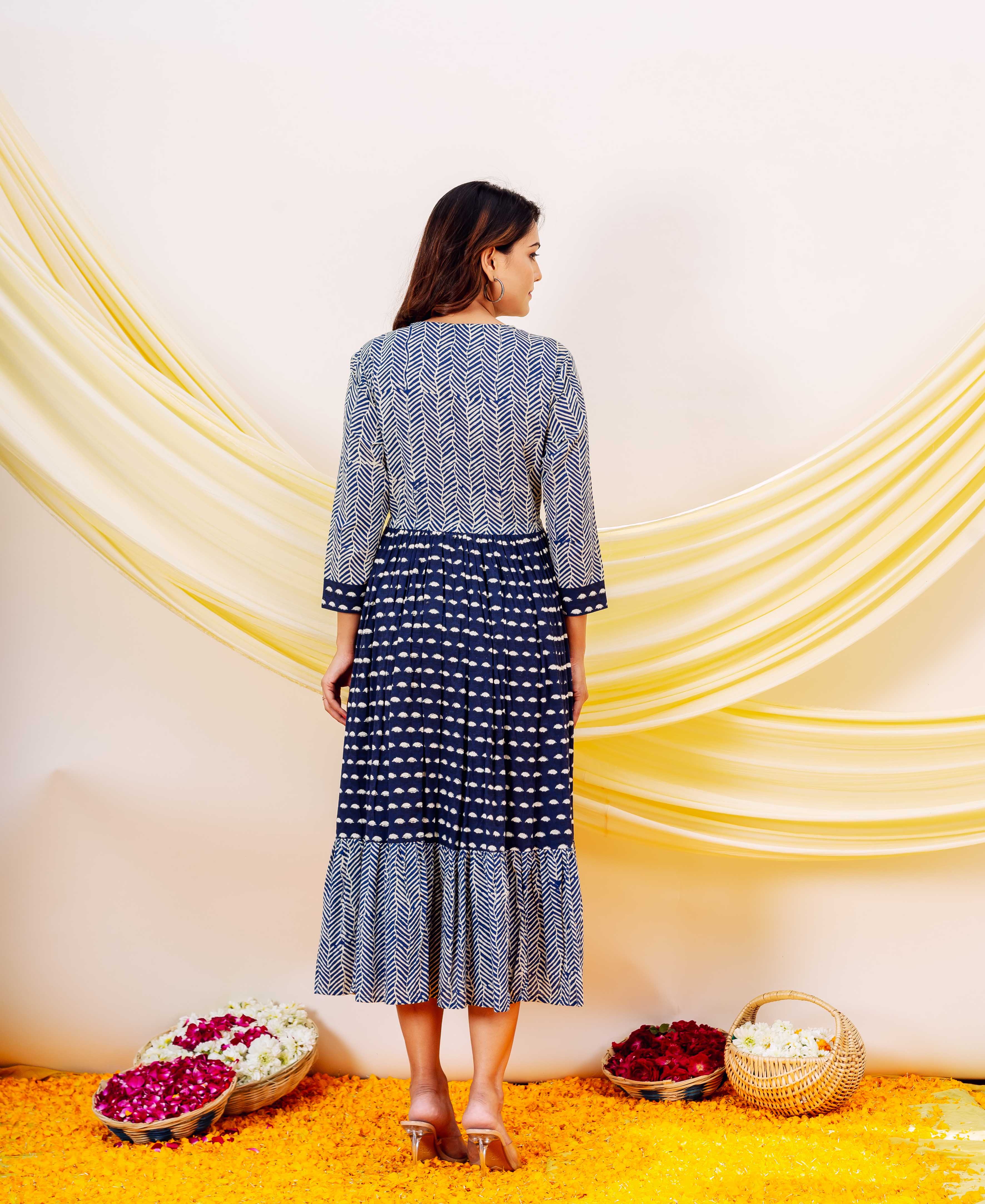 A model wearing a blue and white indigo printed dress with a ruffled hem.
